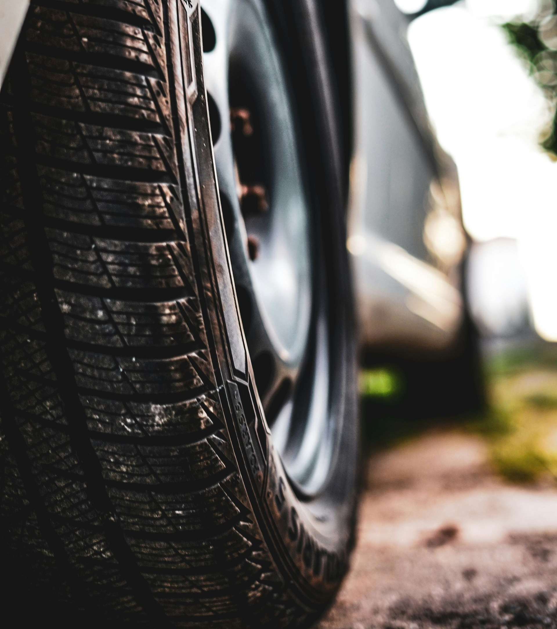 Close-up view of a car tire on a dirt road, captured from a low angle with a shallow depth of field.