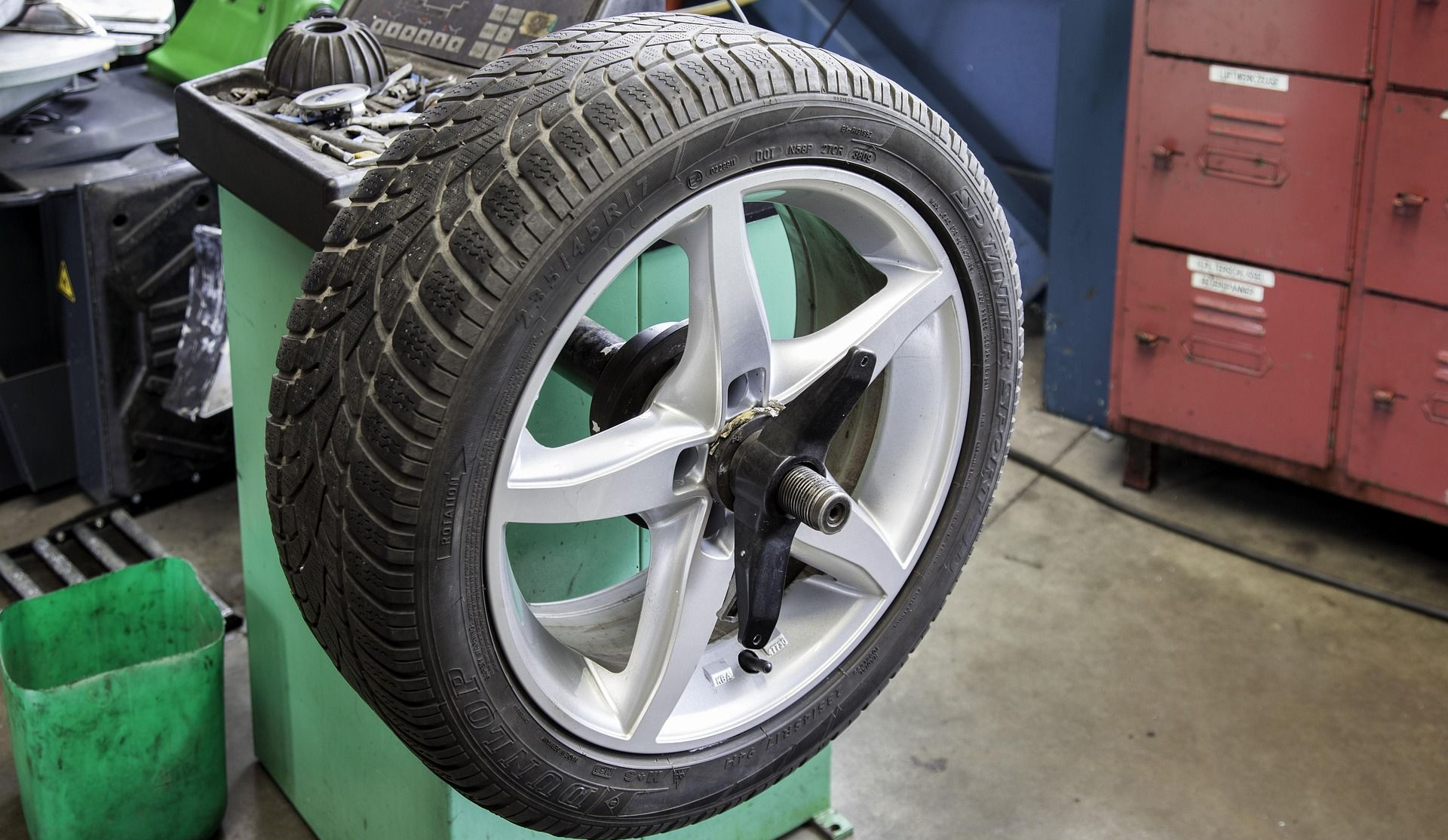 Tire mounted on a balancing machine in a garage.