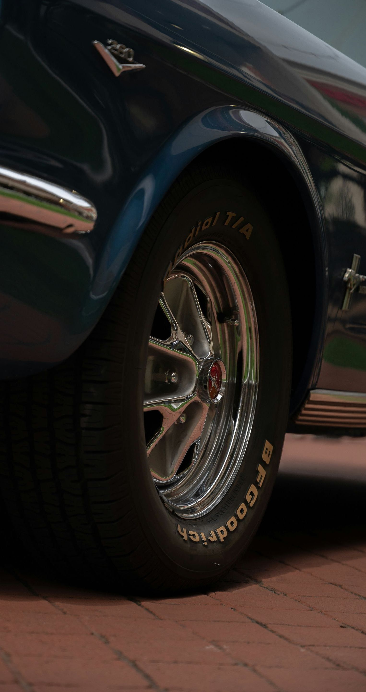 A close up of a car wheel on a brick road.