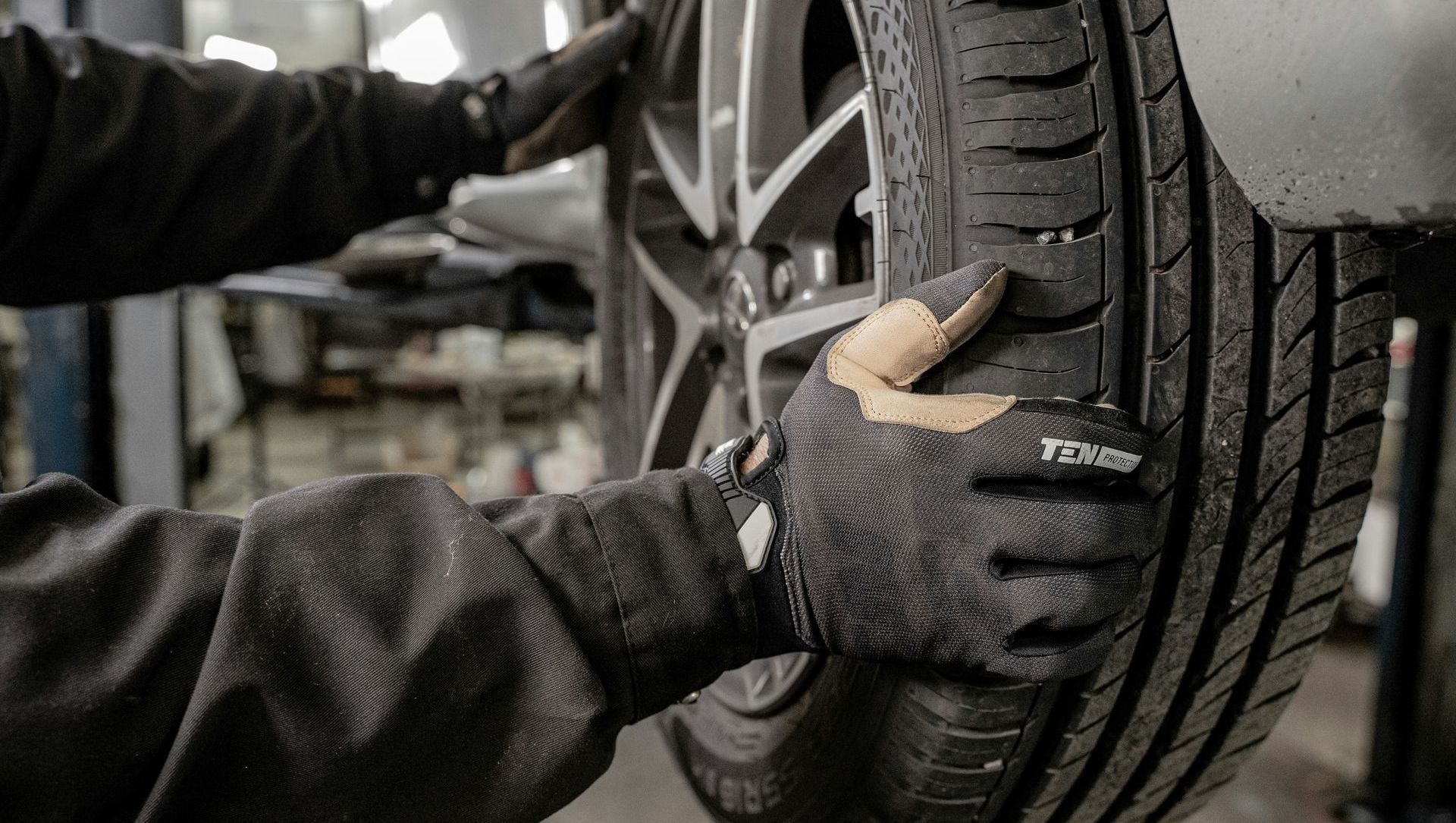 A man is changing a tire on a car in a garage.