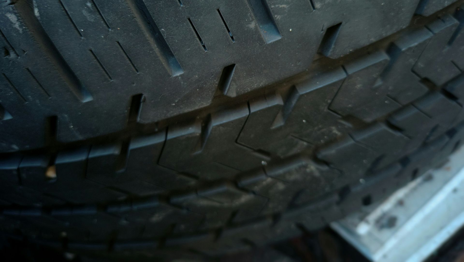 Close-up of a worn black tire with grooves and tread pattern visible, likely for a car or truck.