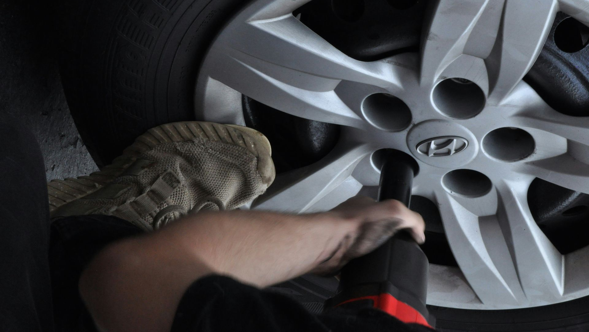 A person uses a tool to tighten a lug nut on a Hyundai car wheel.