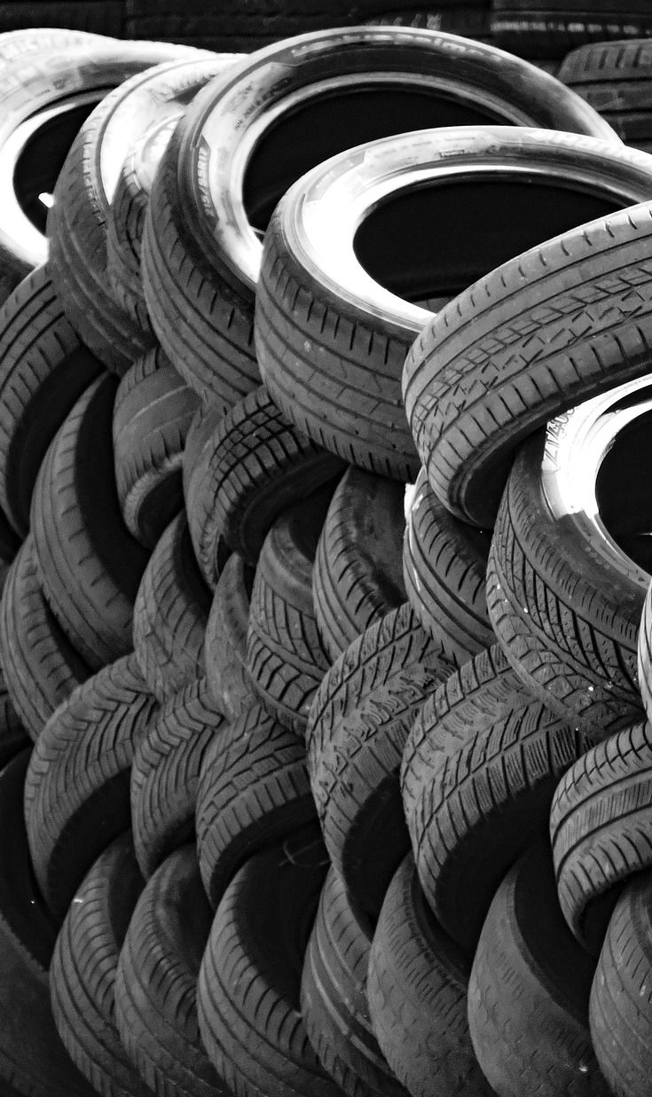 Pile of used tires stacked in a pattern; monochrome.