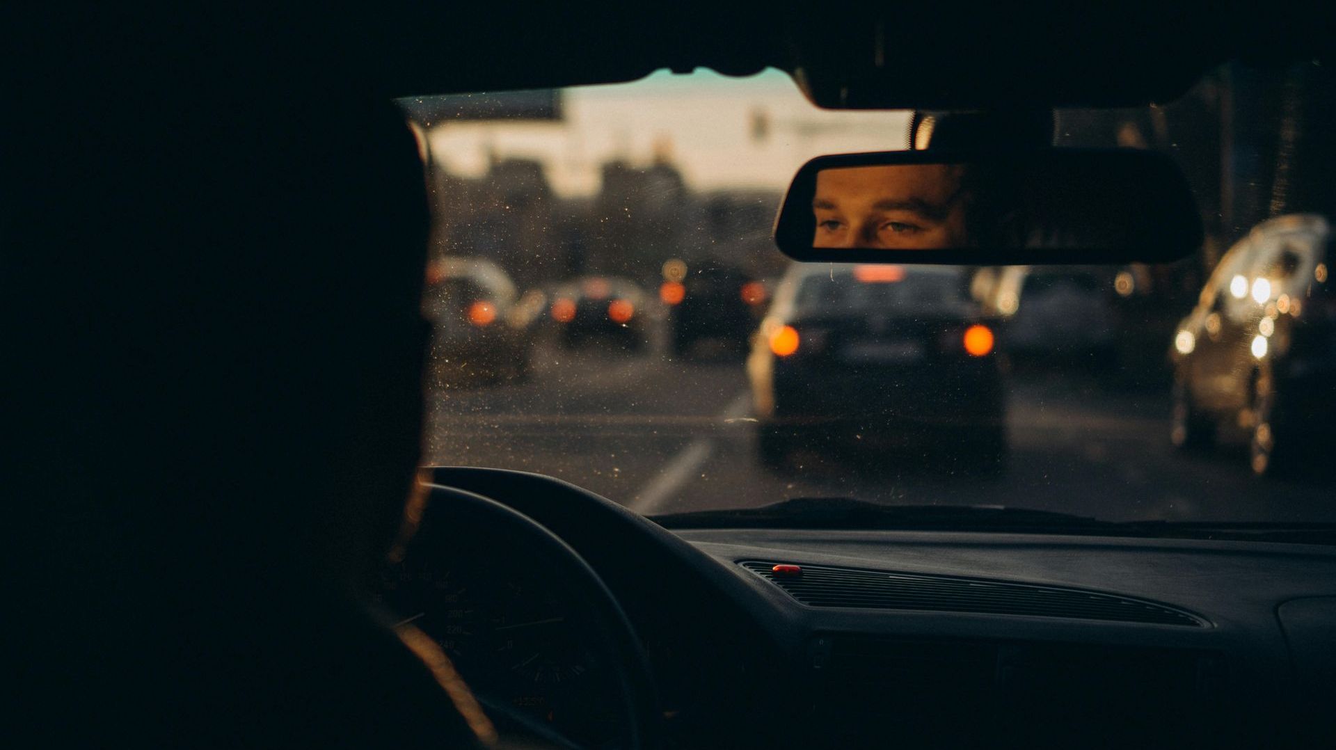 A man is driving a car on a busy highway at night.