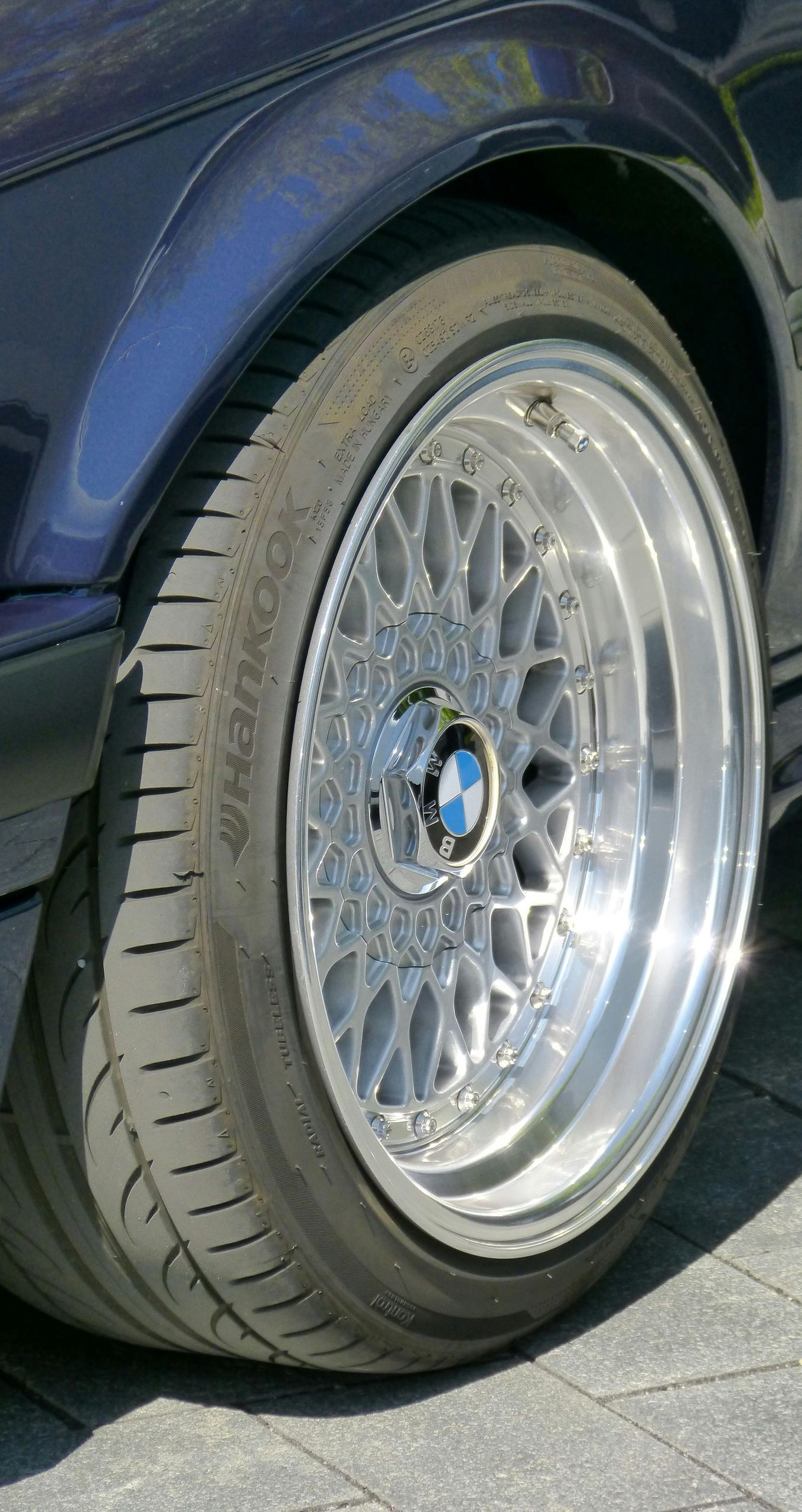 Close-up of a blue car's wheel with a silver, multi-spoke rim.