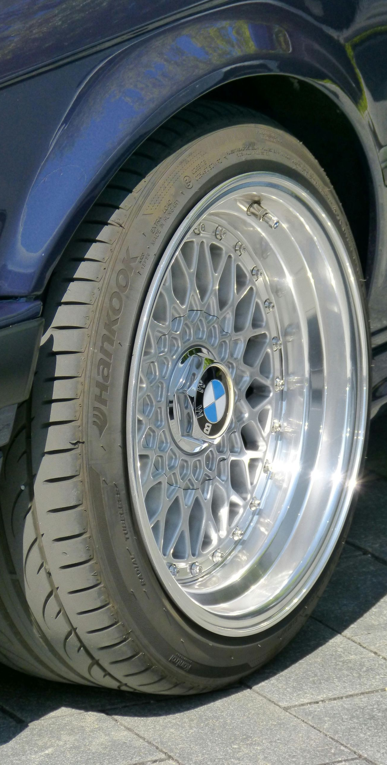 Close-up of a blue car's wheel with a silver, multi-spoke rim.