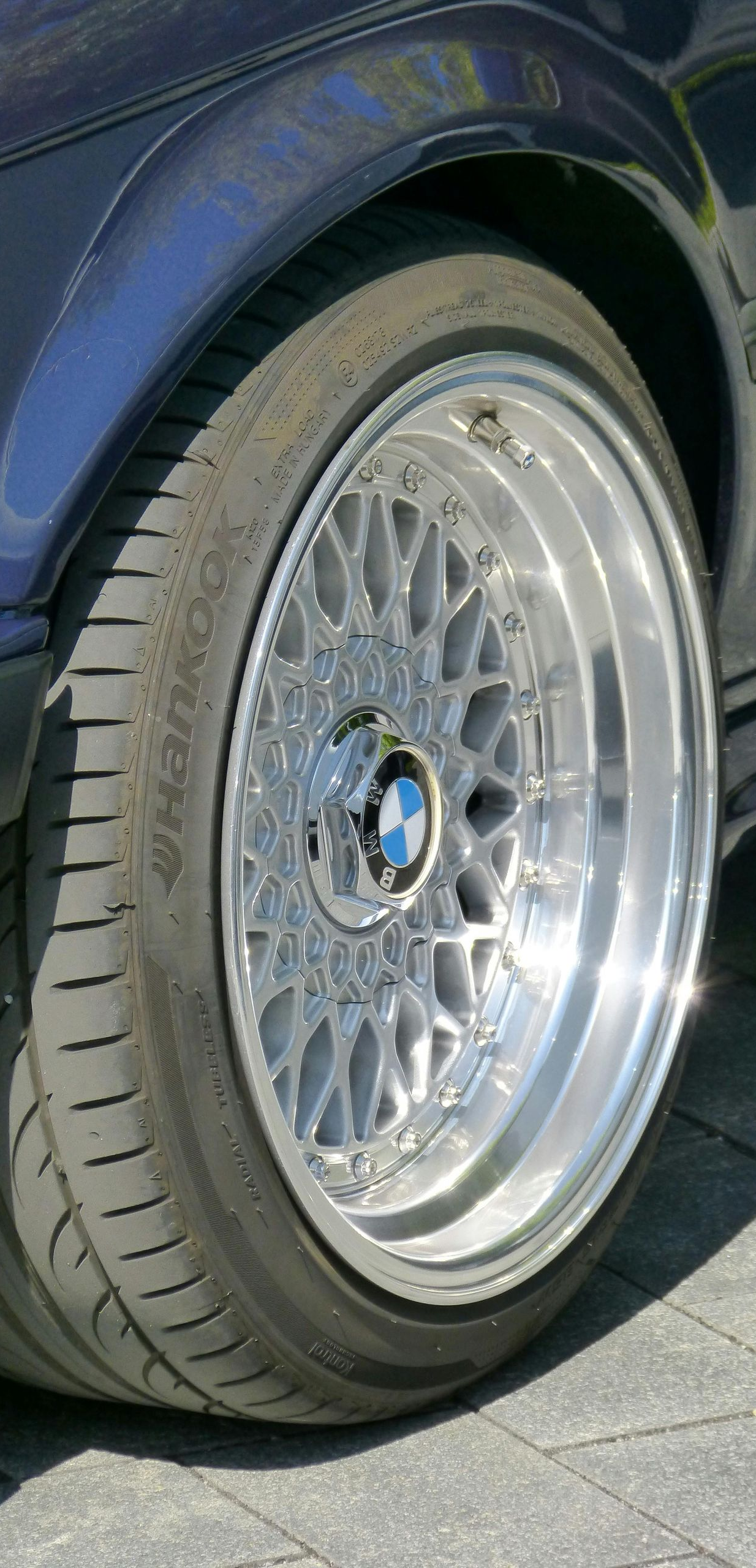 Close-up of a blue car's wheel with a silver, multi-spoke rim.