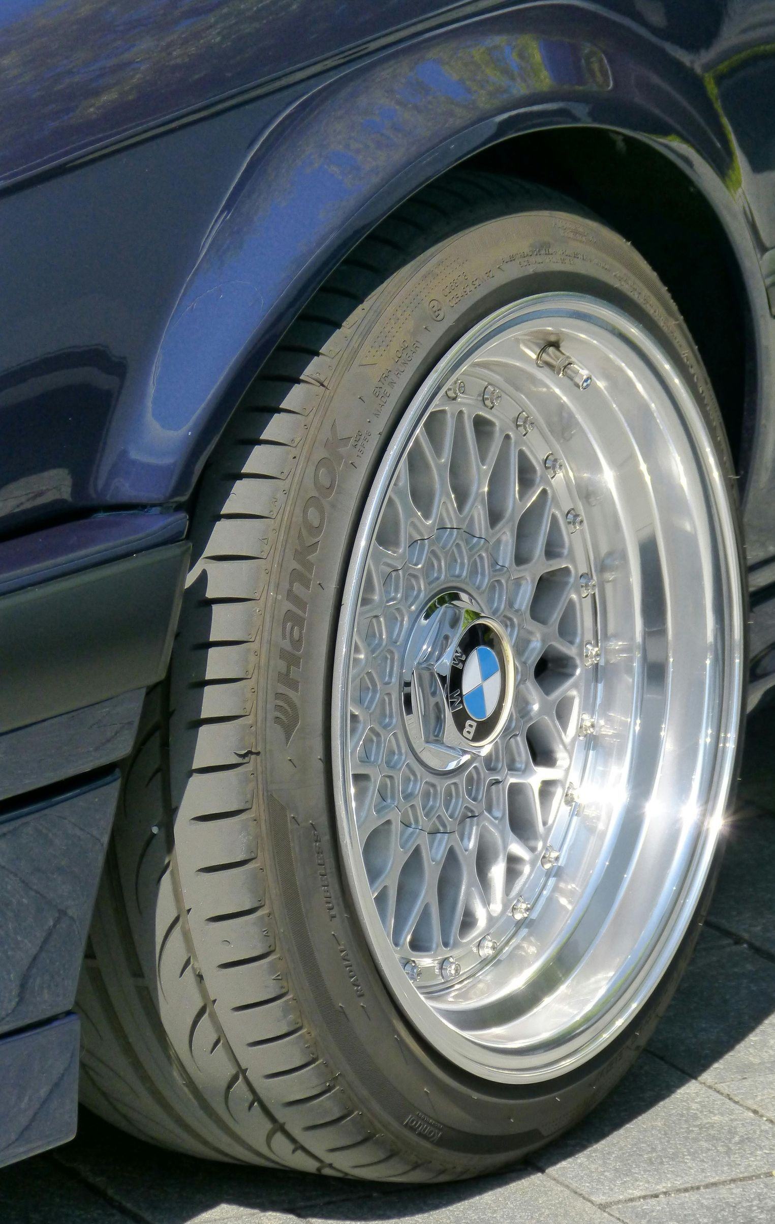 Close-up of a blue car's wheel with a silver, multi-spoke rim.
