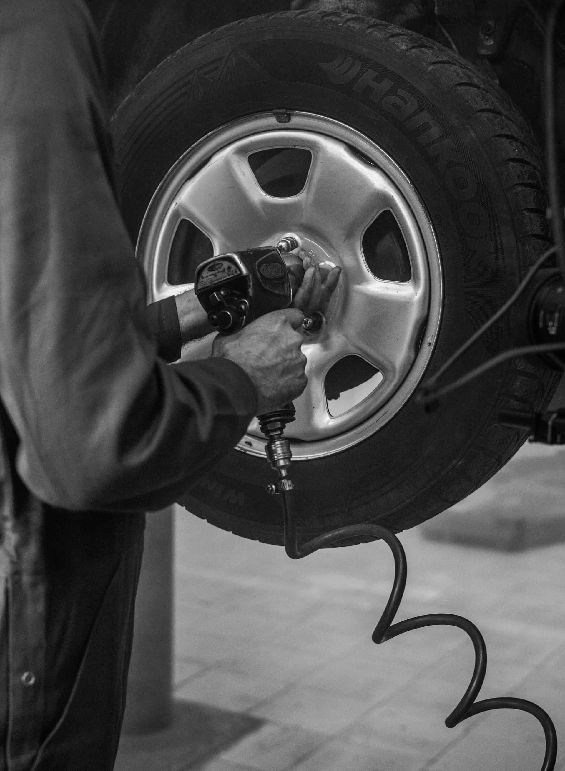 A black and white photo of a man changing a tire