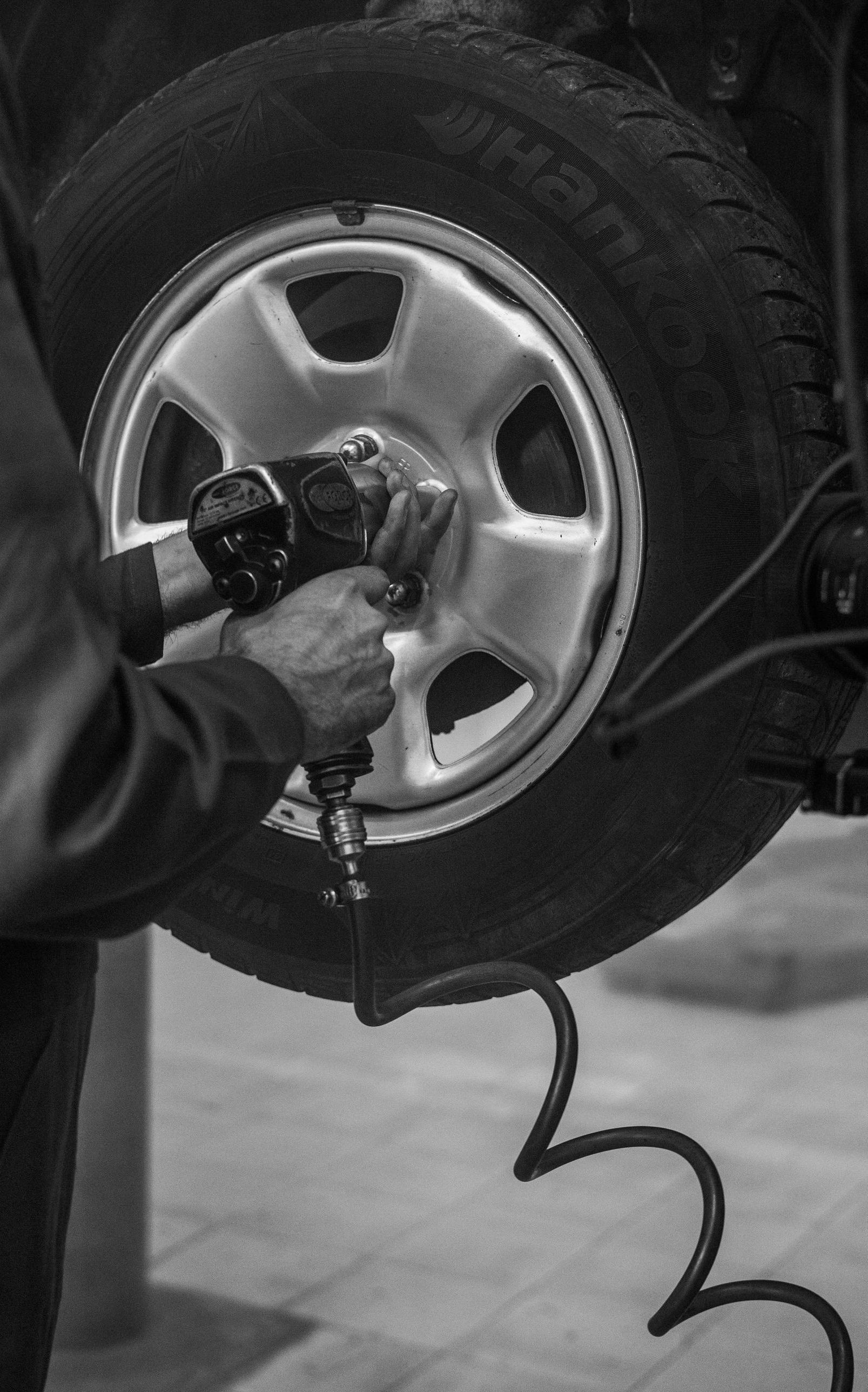 A black and white photo of a man changing a tire