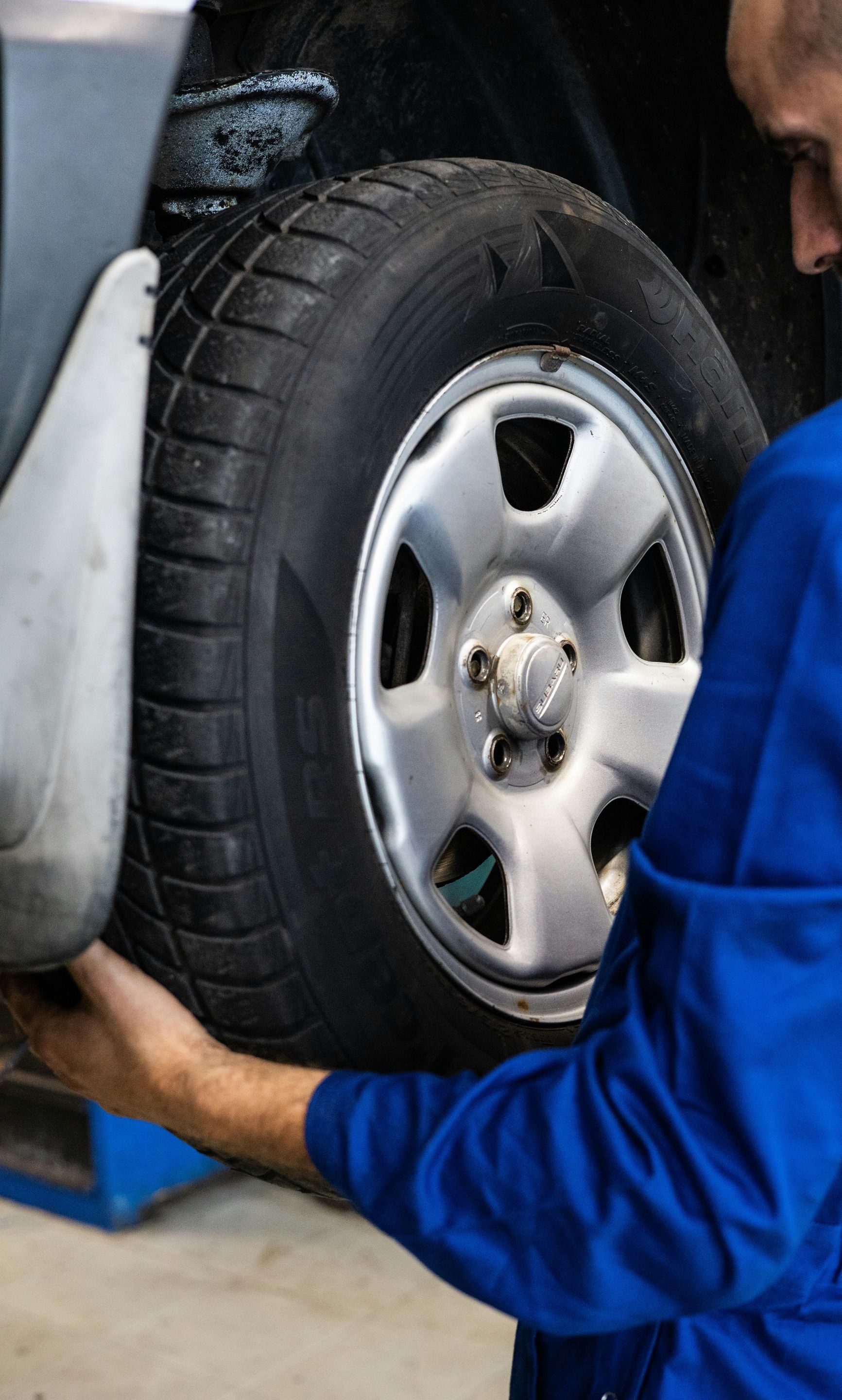 A man in a blue uniform is changing a tire on a car.