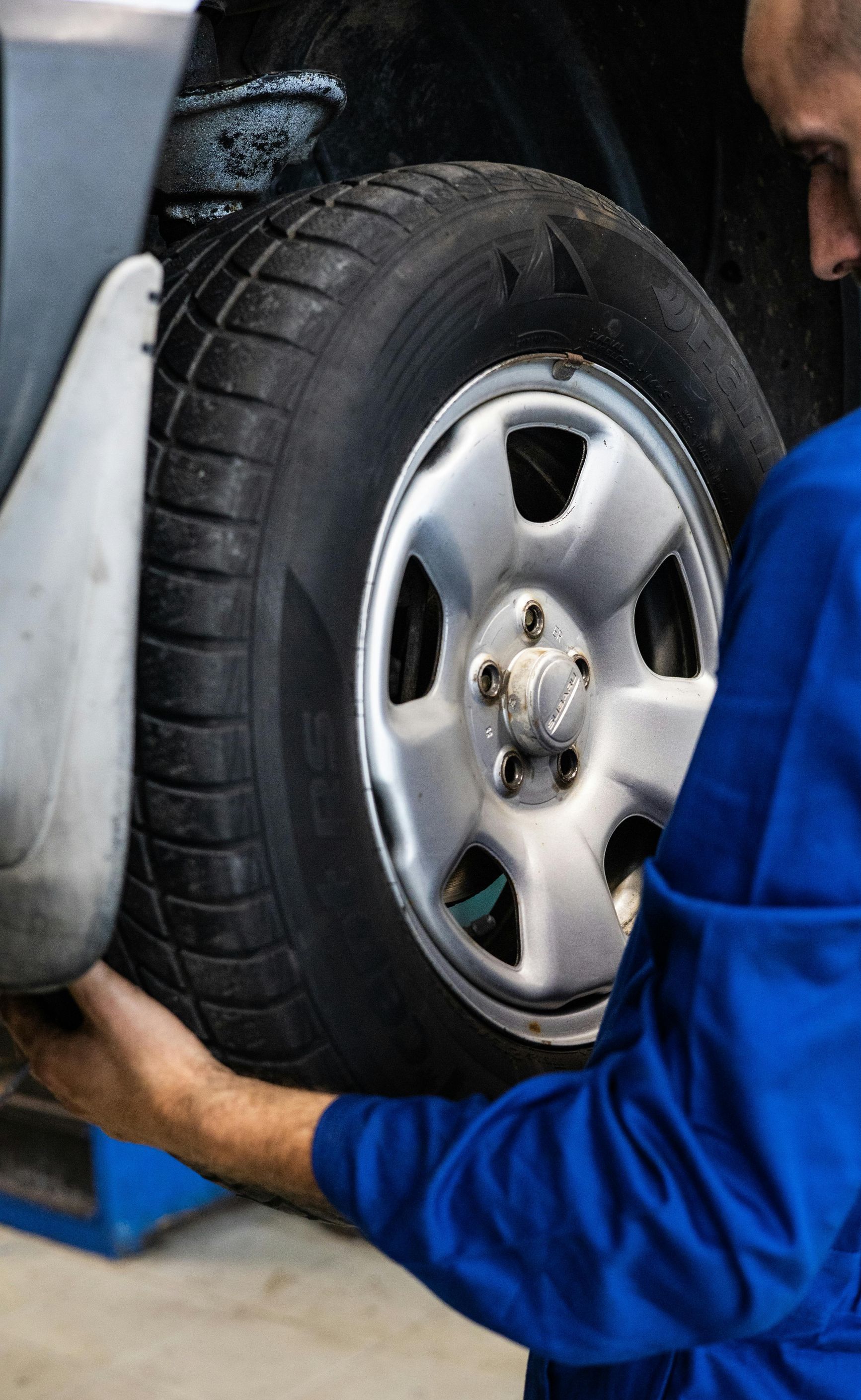 A man in a blue uniform is changing a tire on a car.