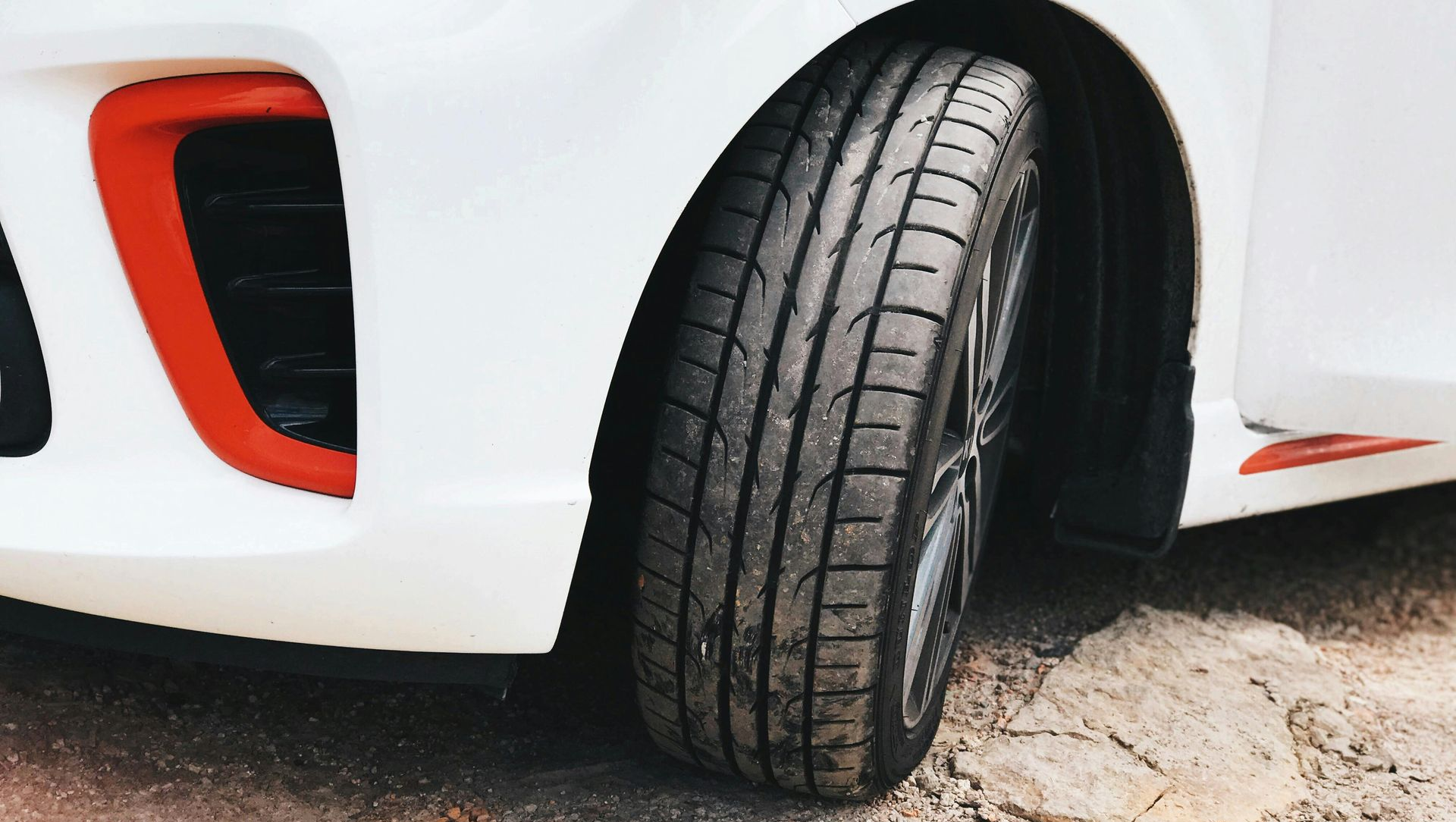 White car tire on dirt, with red trim.