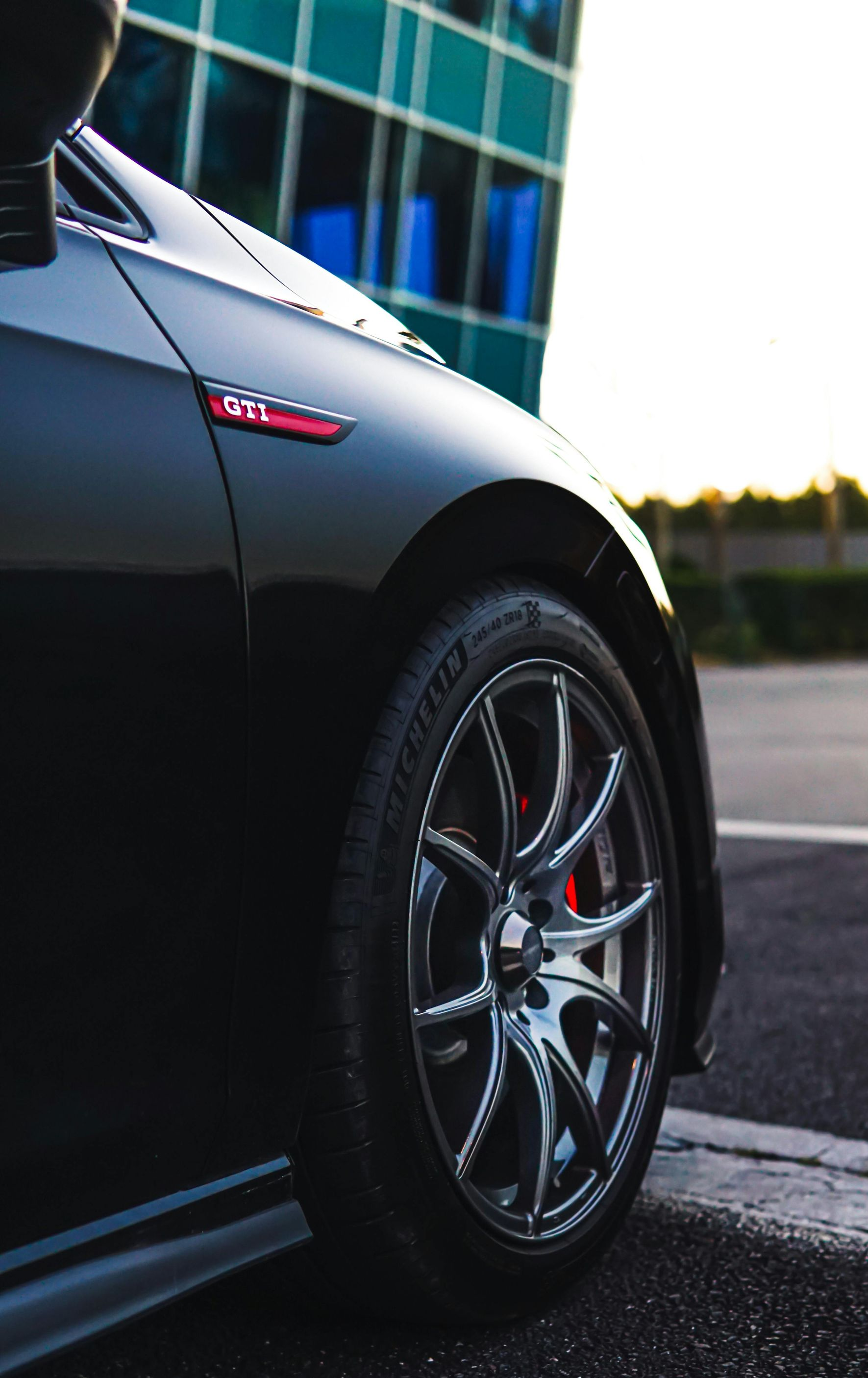 Black VW GTI car with red brake calipers, side view, parked near a building.