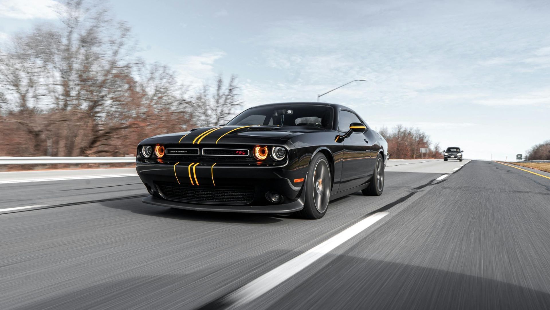 A black dodge challenger is driving down a highway.
