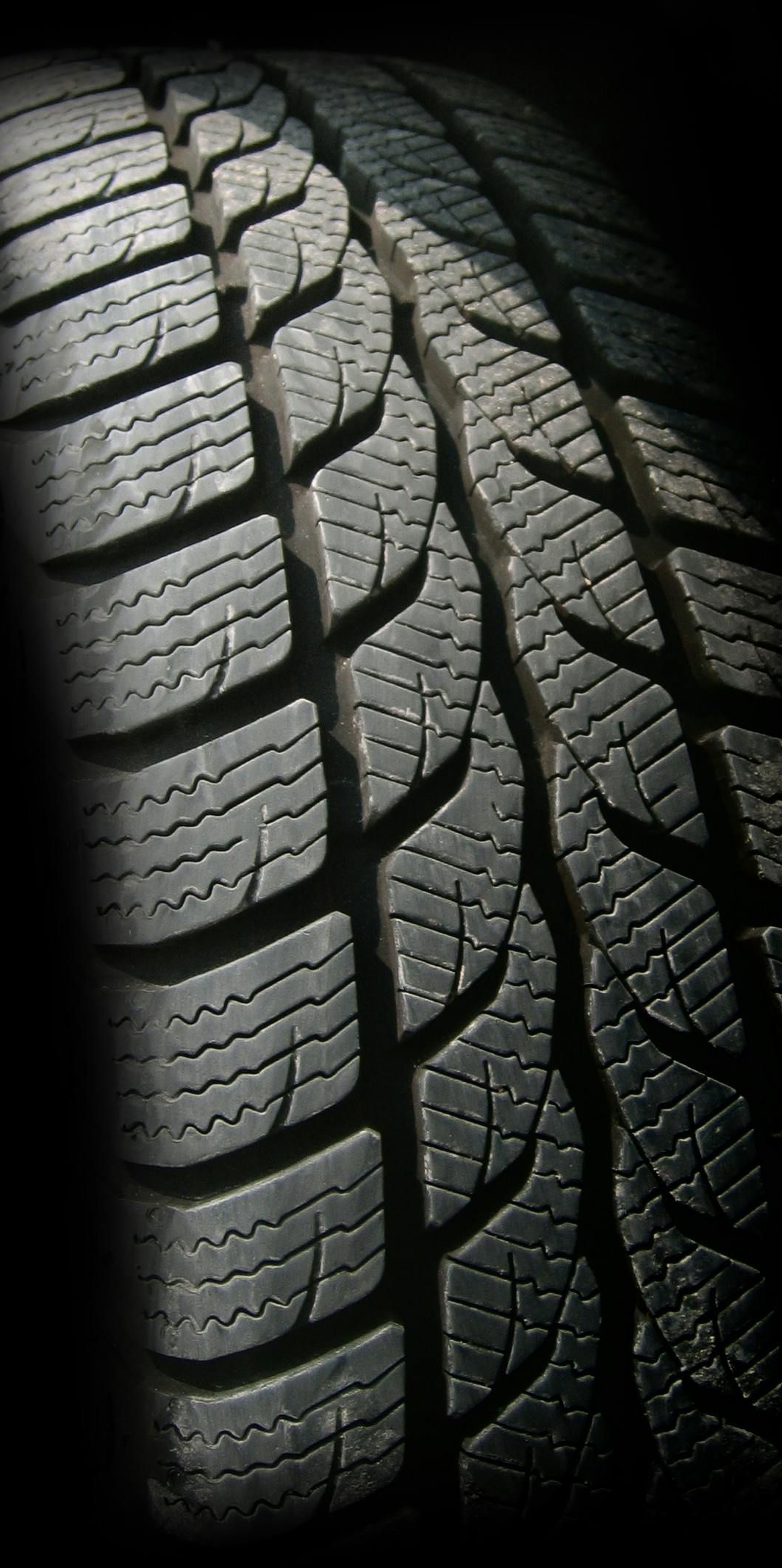 Close-up of a black tire with deep tread patterns.