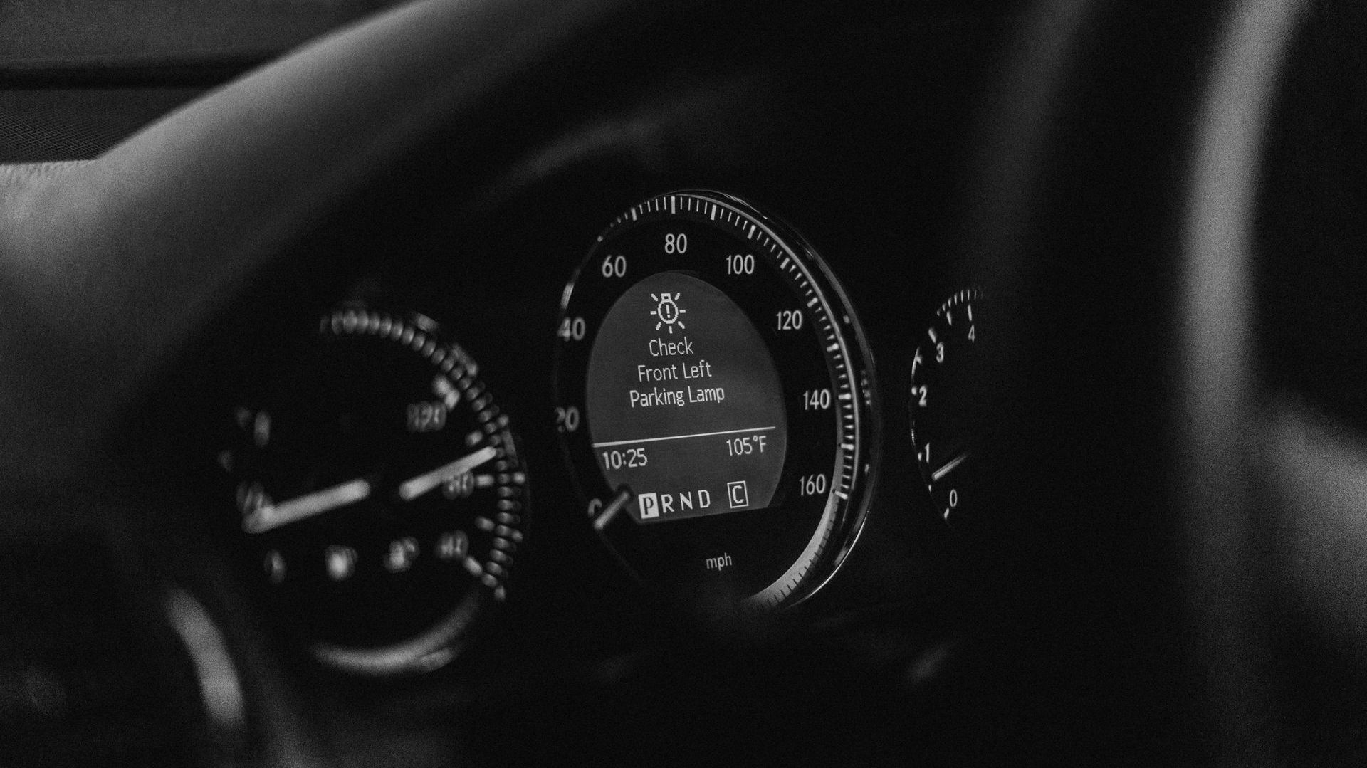 A black and white photo of the dashboard of a car.