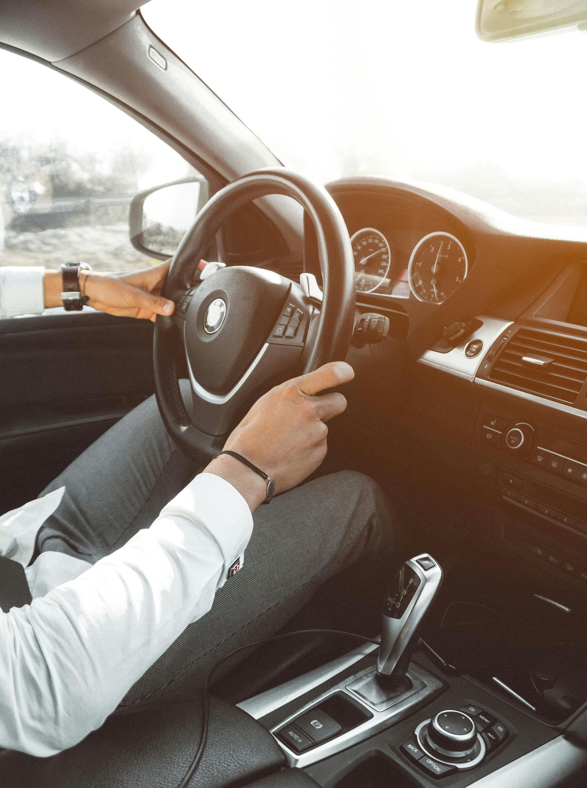 A man is driving a car with his hands on the steering wheel.