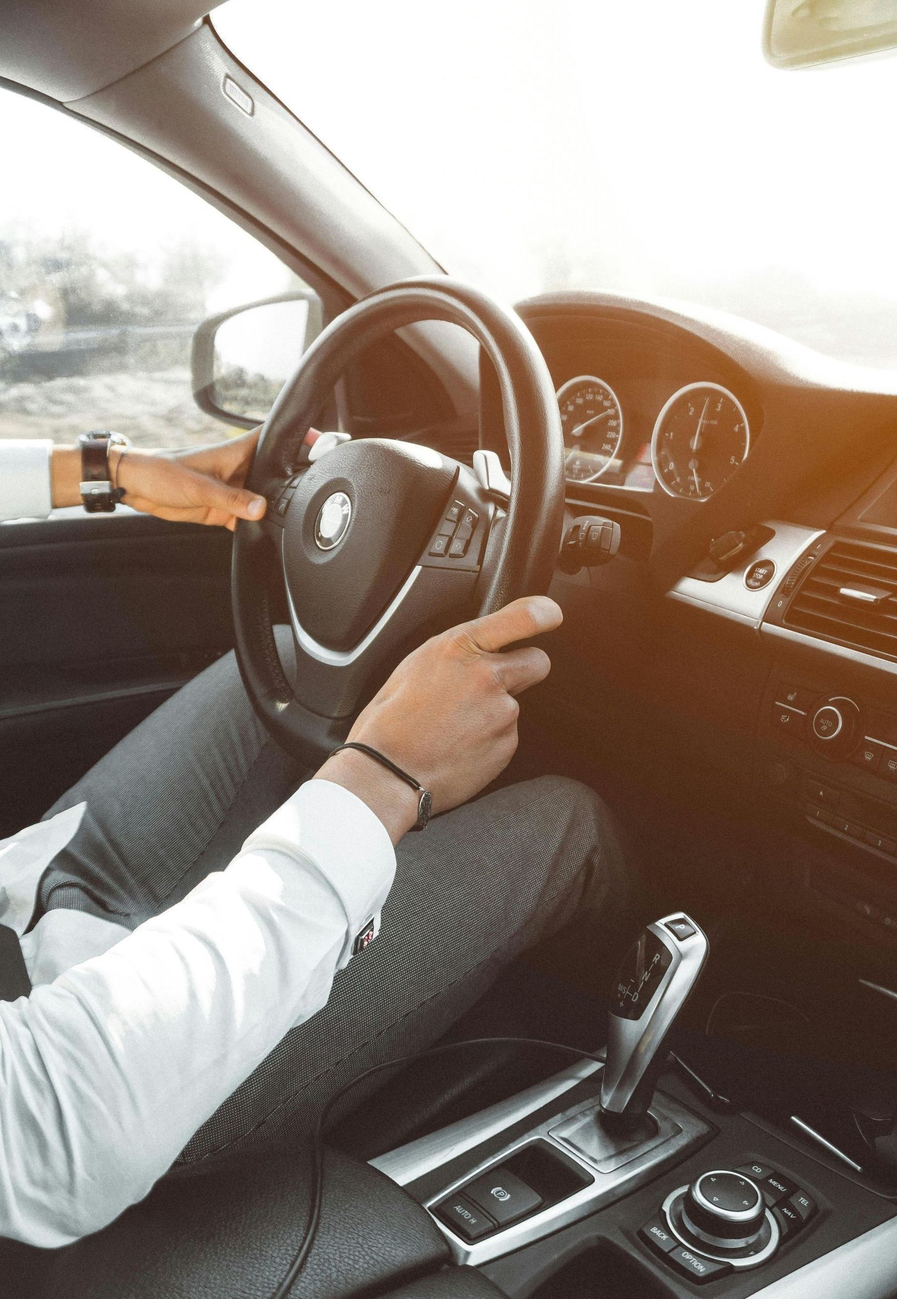 A man is driving a car with his hands on the steering wheel.
