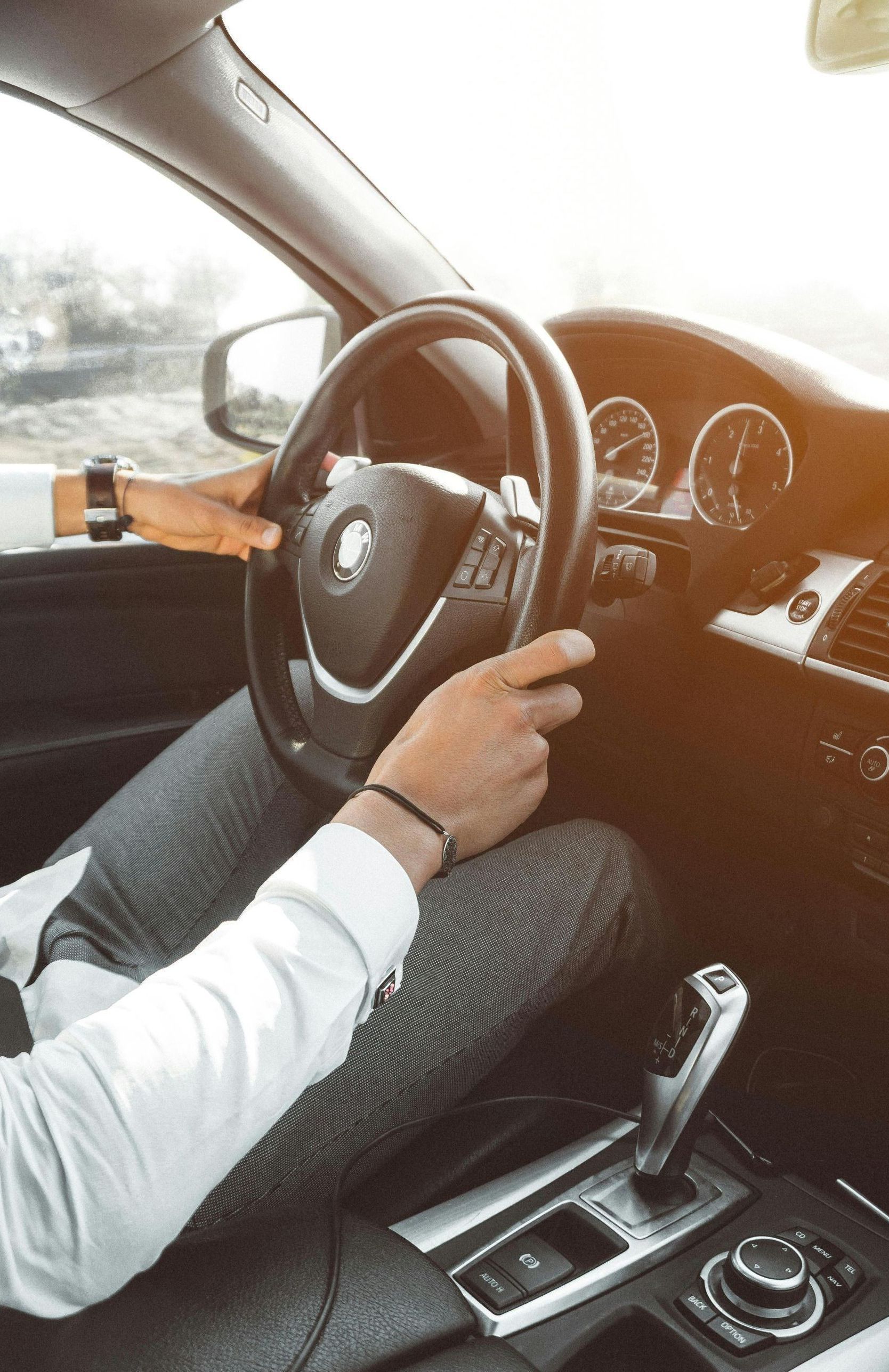 A man is driving a car with his hands on the steering wheel.
