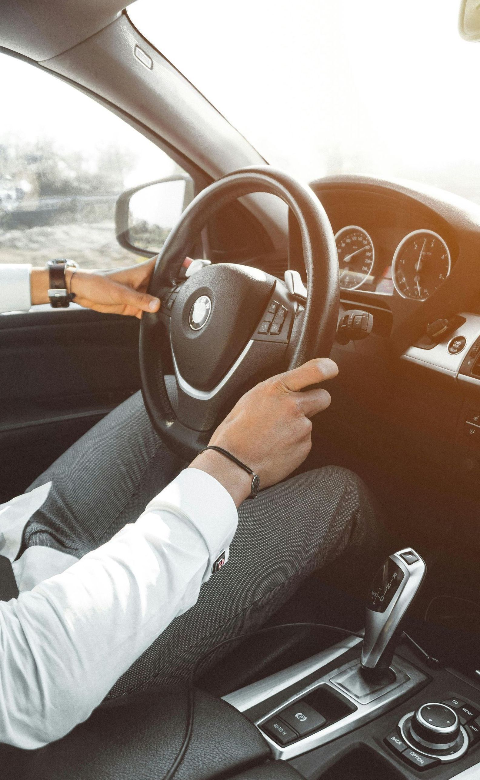 A man is driving a car with his hands on the steering wheel.