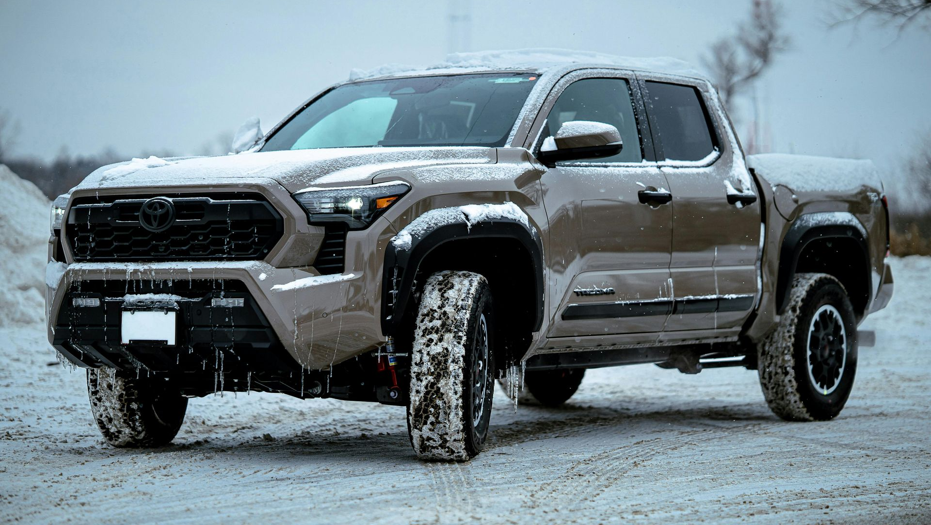 Brown Toyota Tacoma pickup truck in a snowy landscape.
