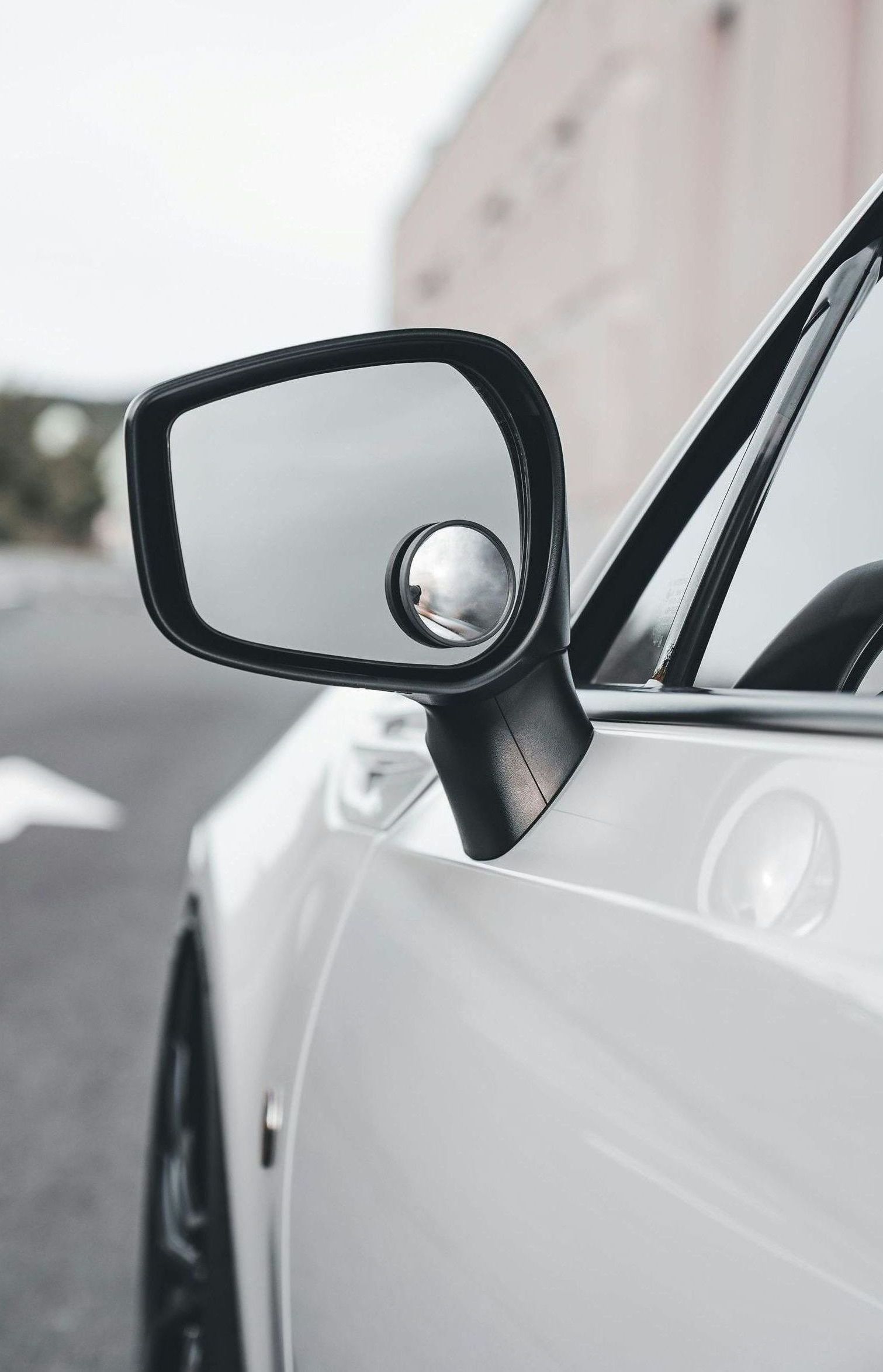 A close up of a side view mirror on a white car.