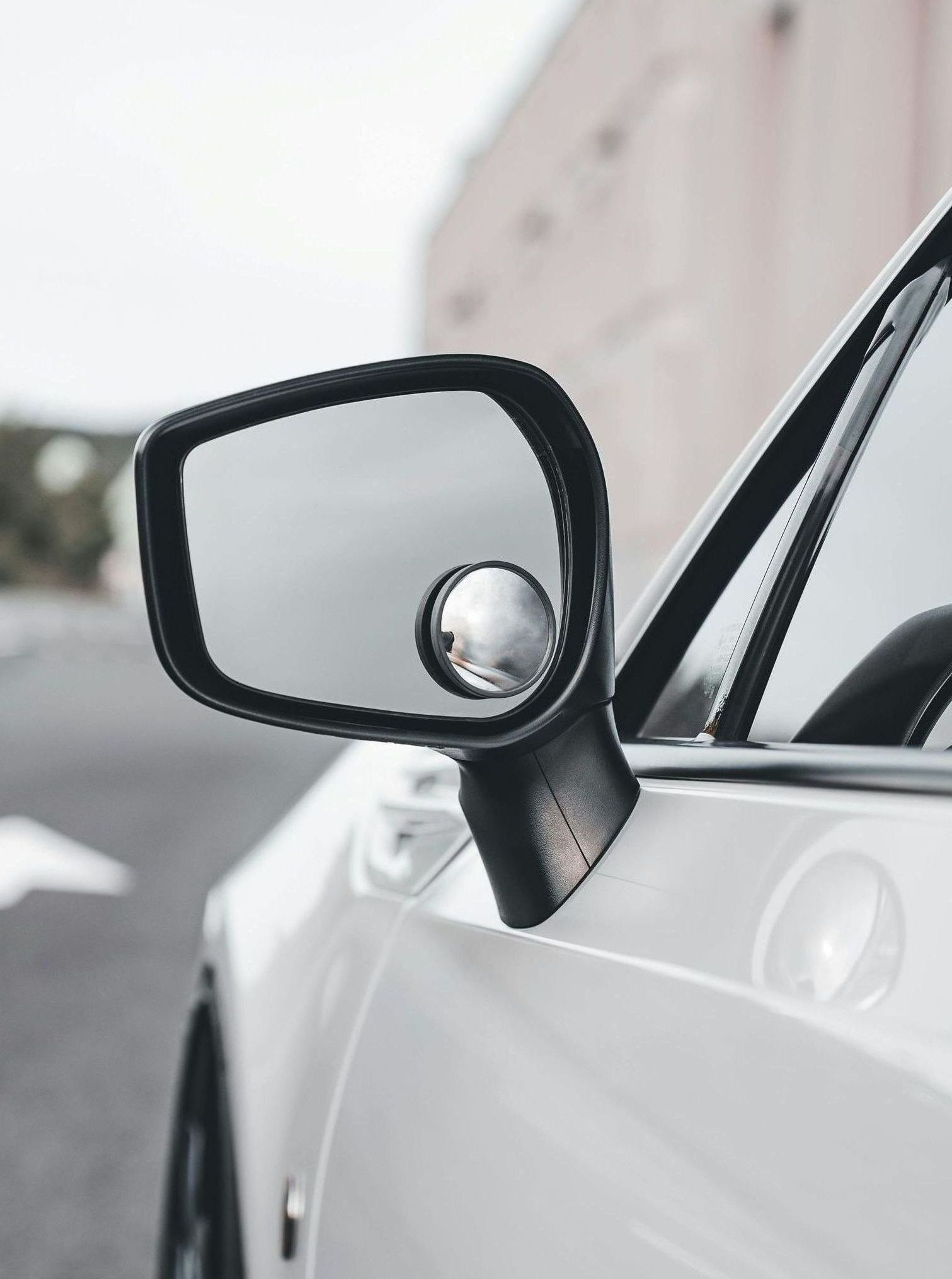 A close up of a side view mirror on a white car.