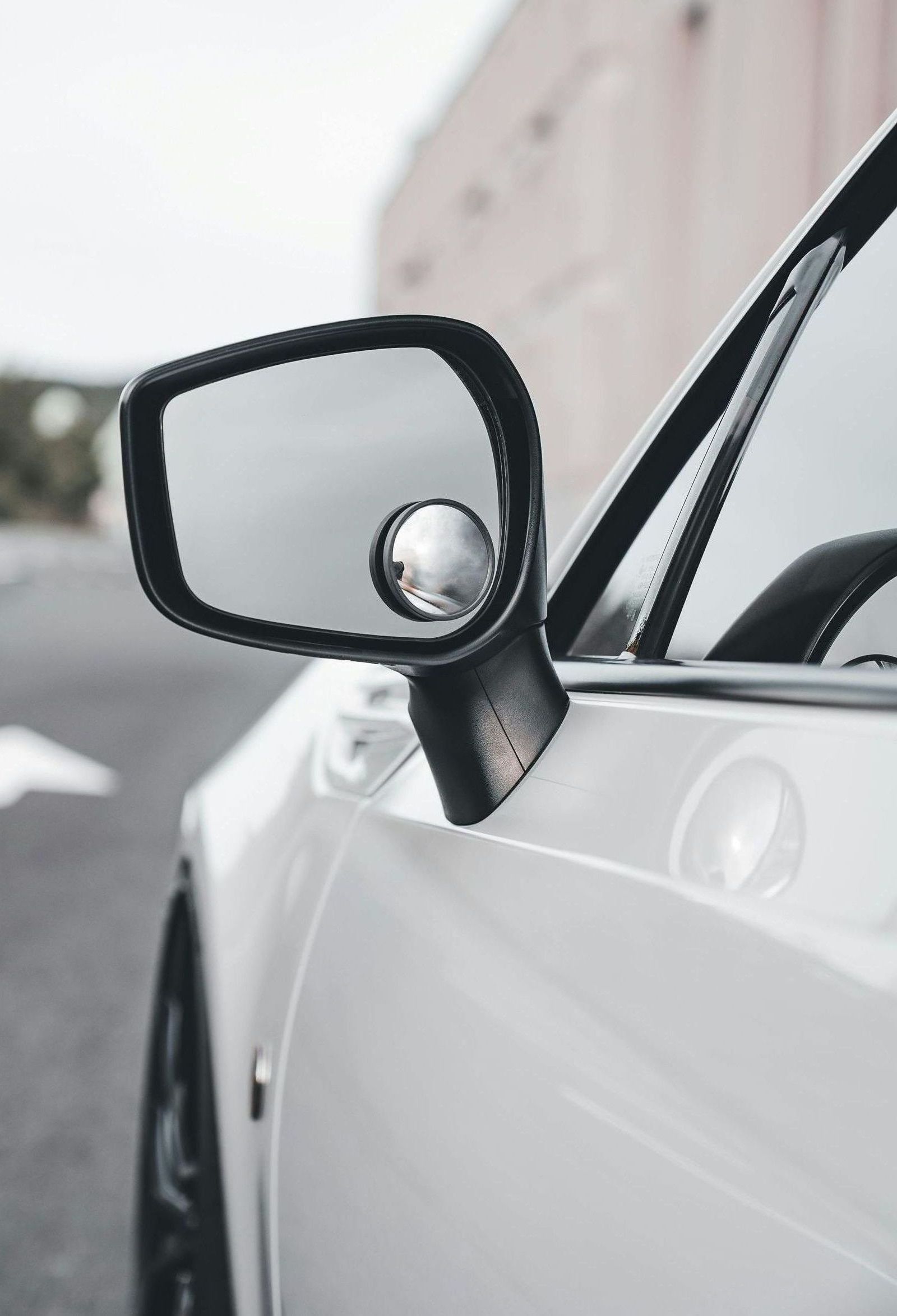 A close up of a side view mirror on a white car.