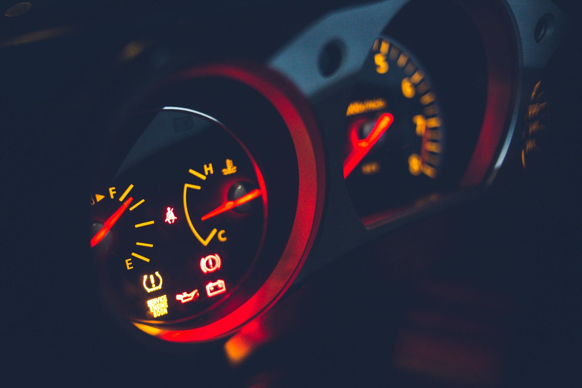 A close up of a car dashboard with a red light on