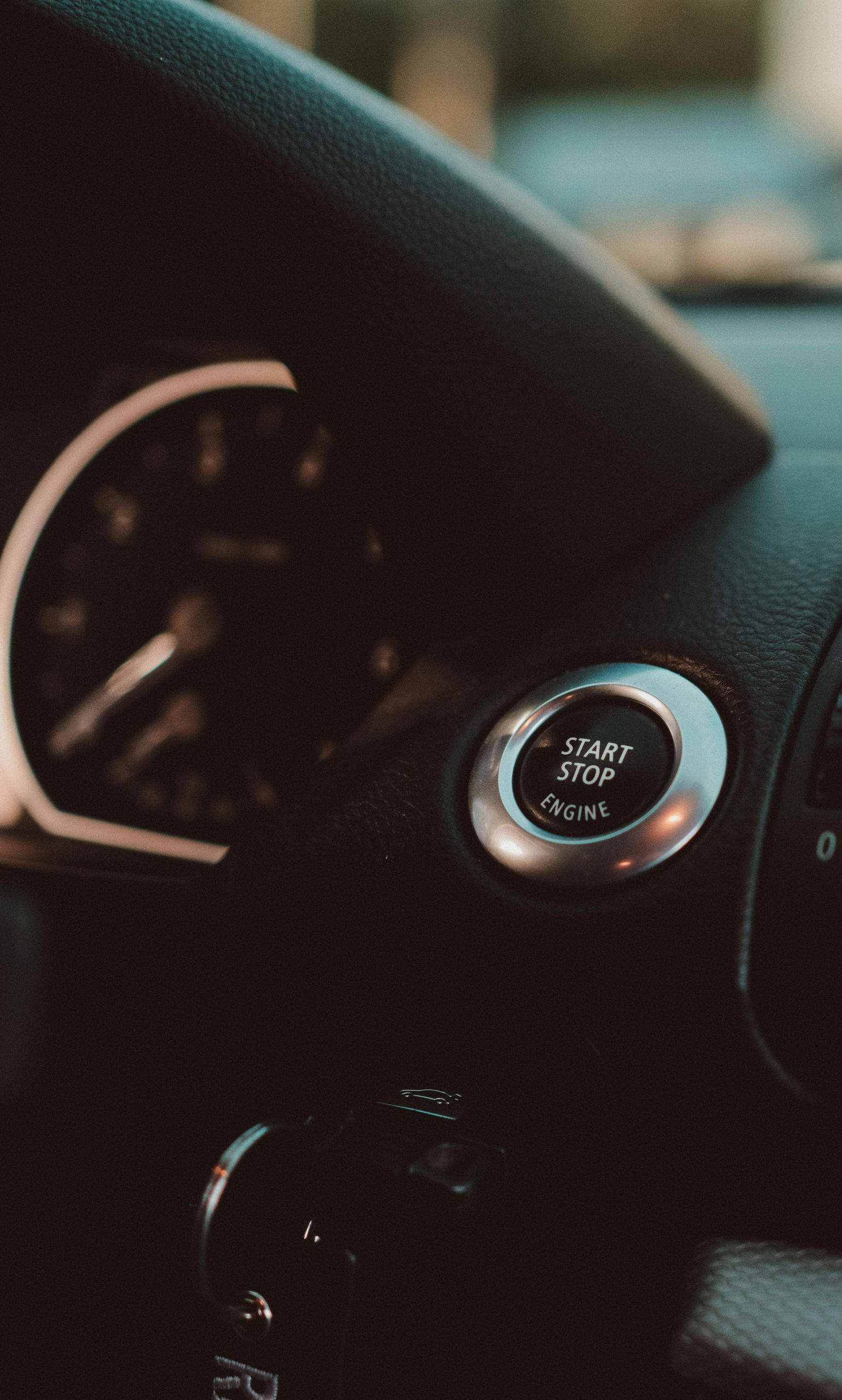 Dashboard with a start/stop button and speedometer in a car.