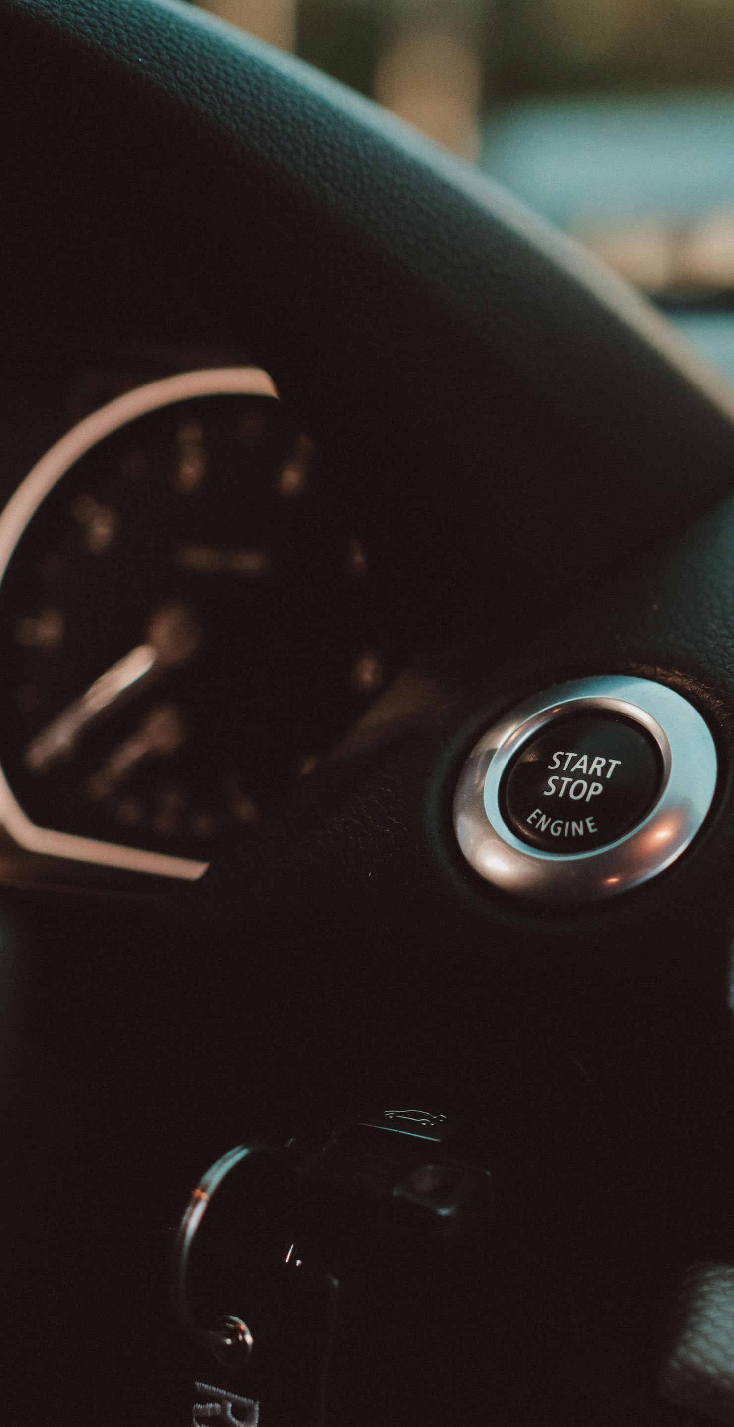 Dashboard with a start/stop button and speedometer in a car.