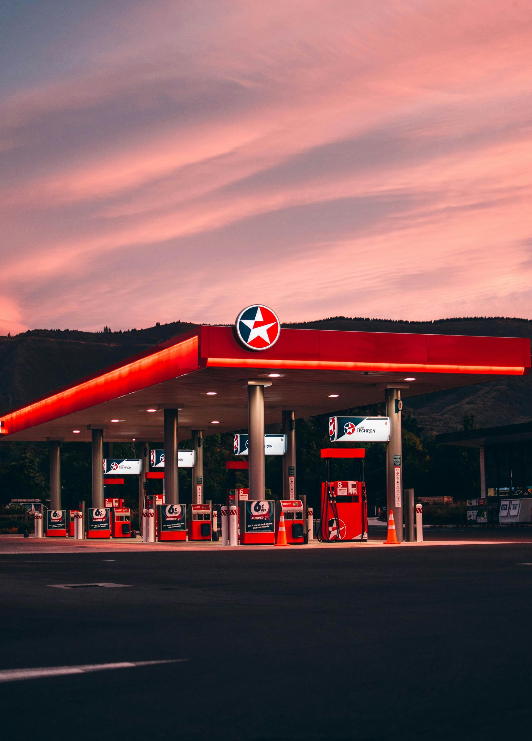 Gas station with red canopy and Texaco sign at sunset.