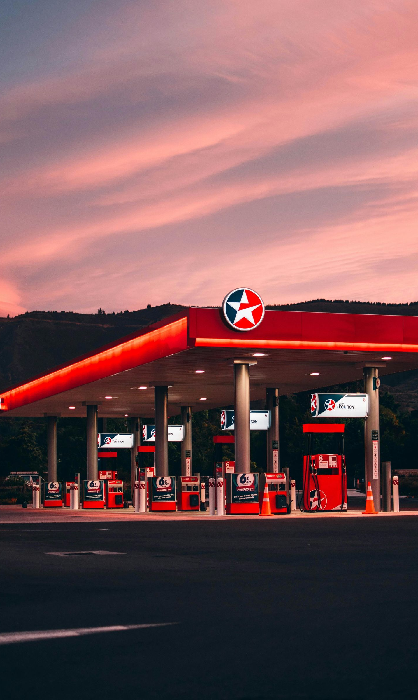 Gas station with red canopy and Texaco sign at sunset.