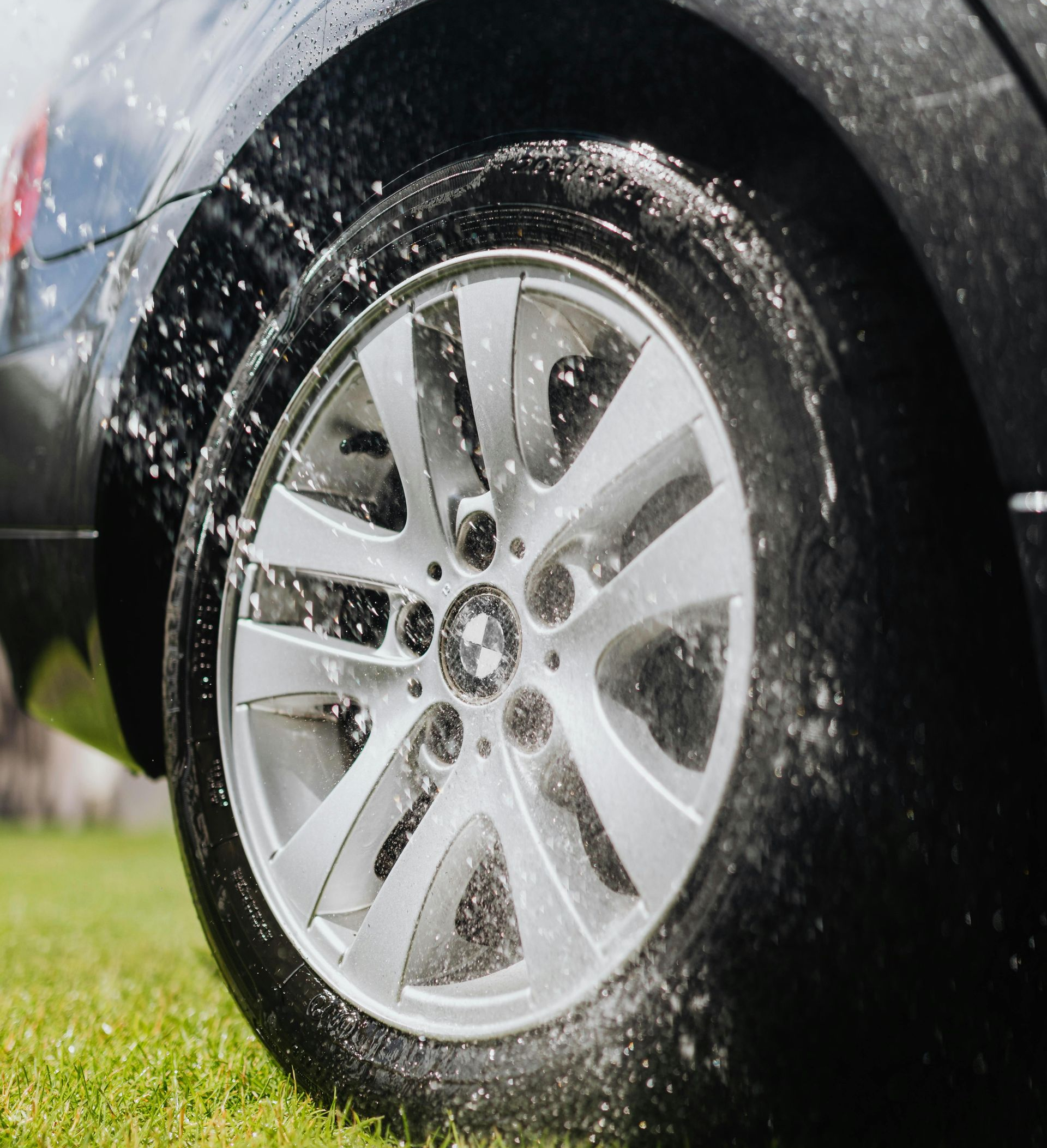Car tire being sprayed with water and suds during washing.