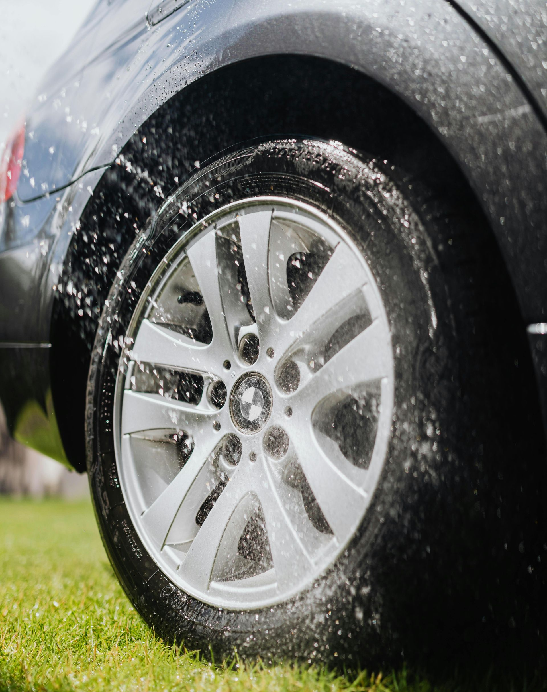 Car tire being sprayed with water and suds during washing.