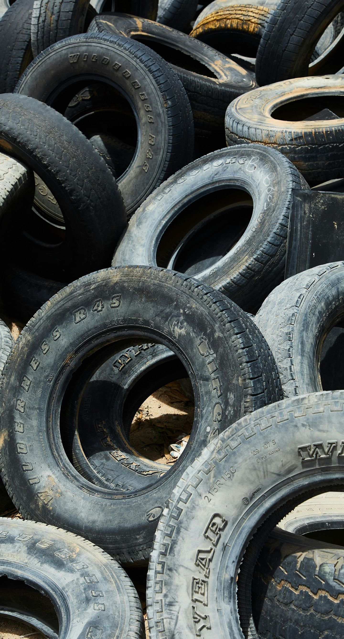Pile of old tires, mostly black and gray, with some worn white lettering visible.