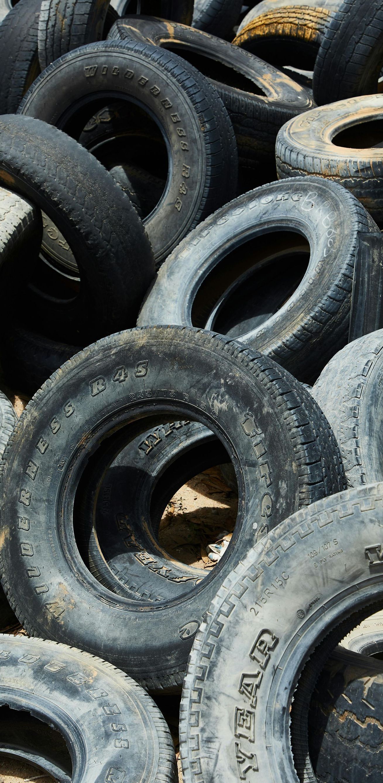 Pile of old tires, mostly black and gray, with some worn white lettering visible.