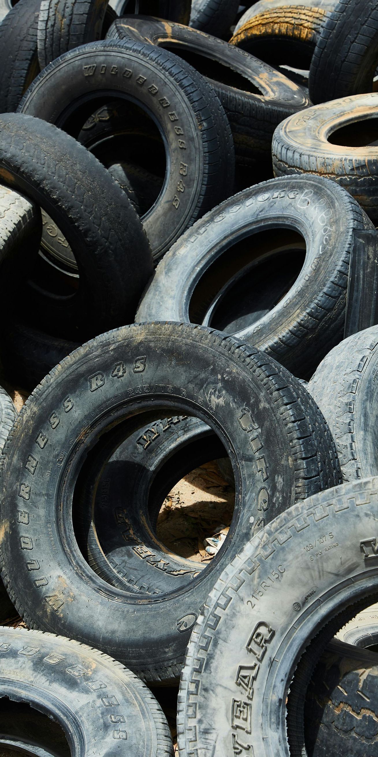 Pile of old tires, mostly black and gray, with some worn white lettering visible.