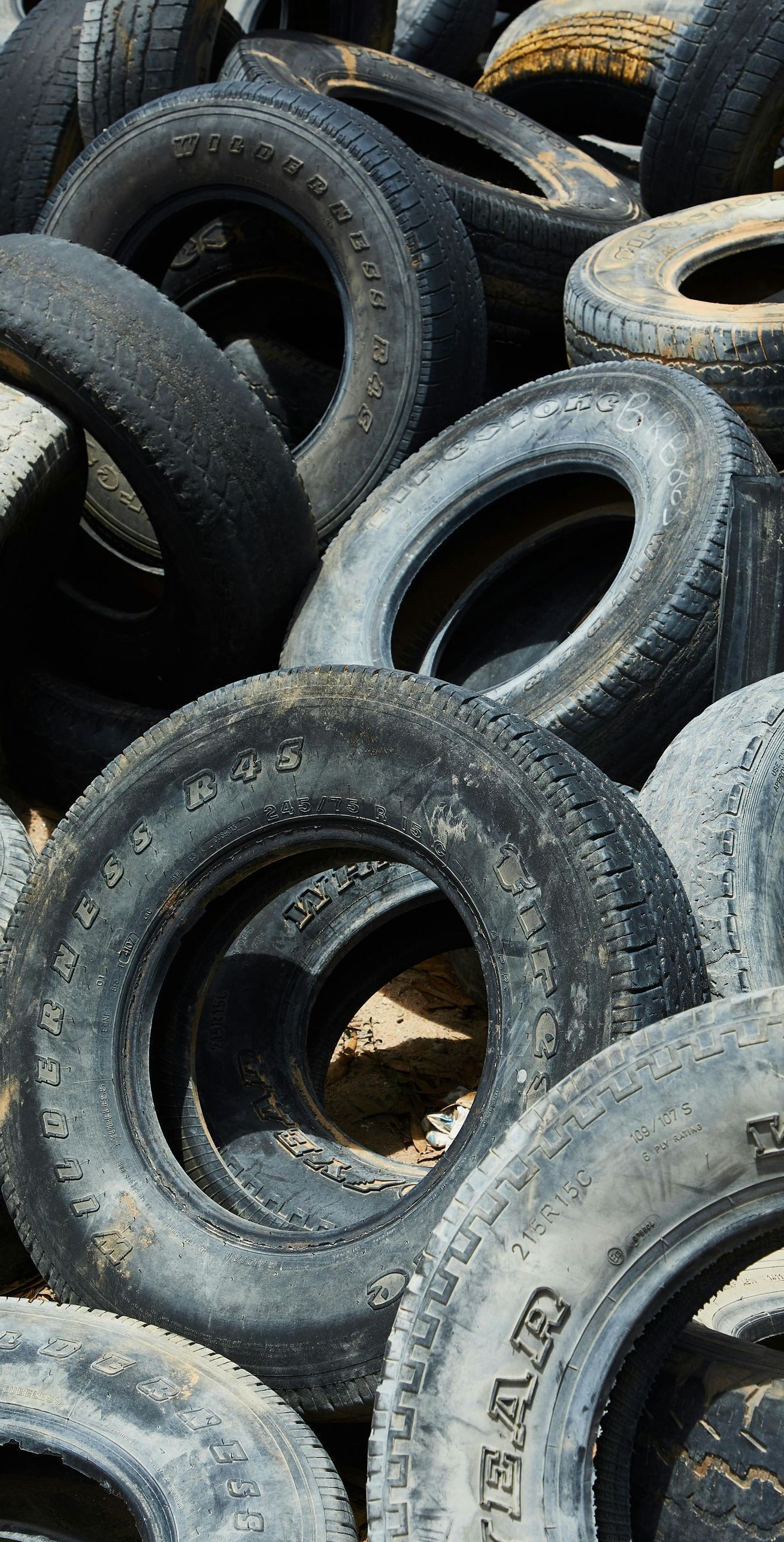 Pile of old tires, mostly black and gray, with some worn white lettering visible.