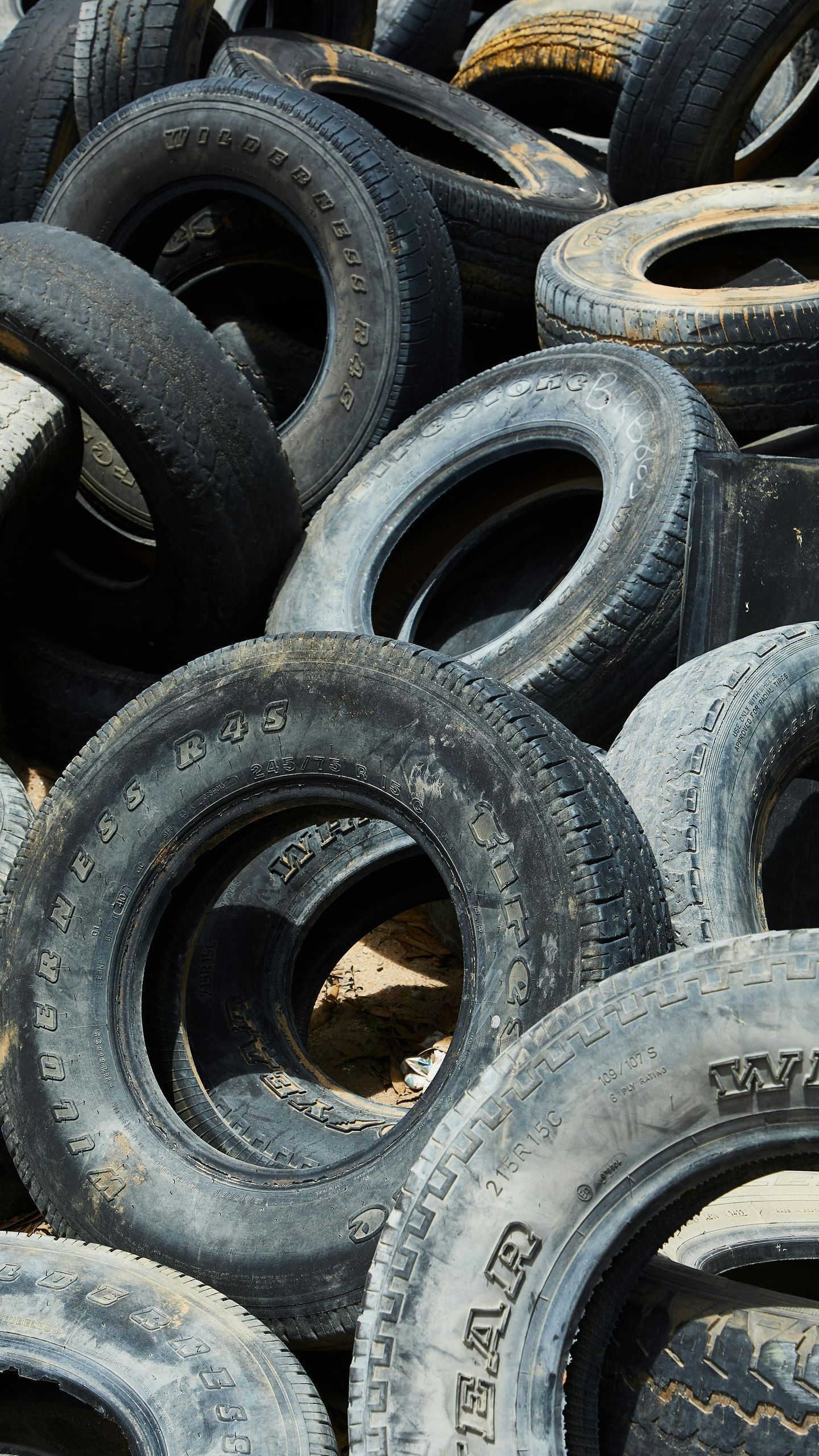 Pile of old tires, mostly black and gray, with some worn white lettering visible.