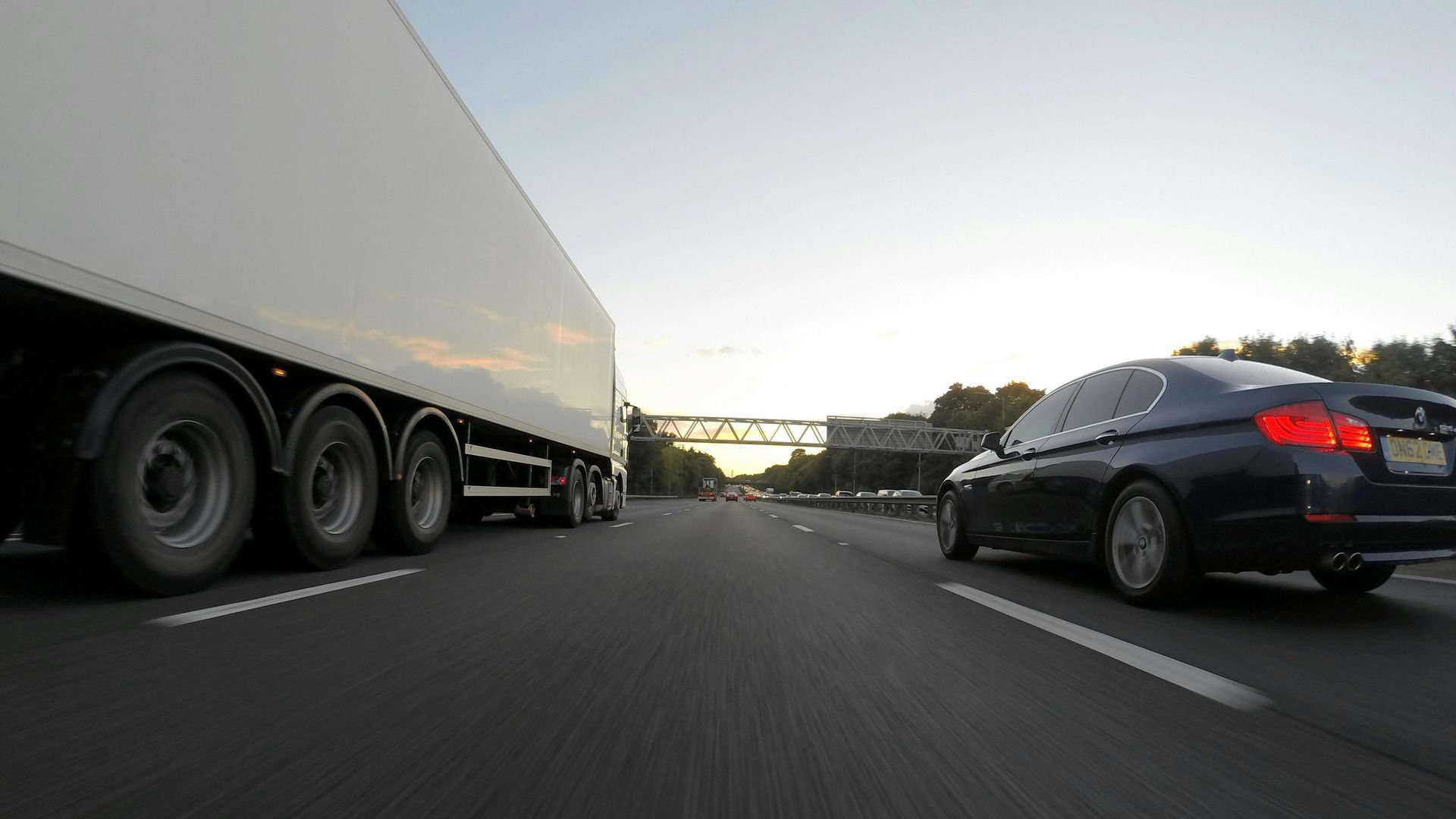 A truck and a car are driving down a highway.