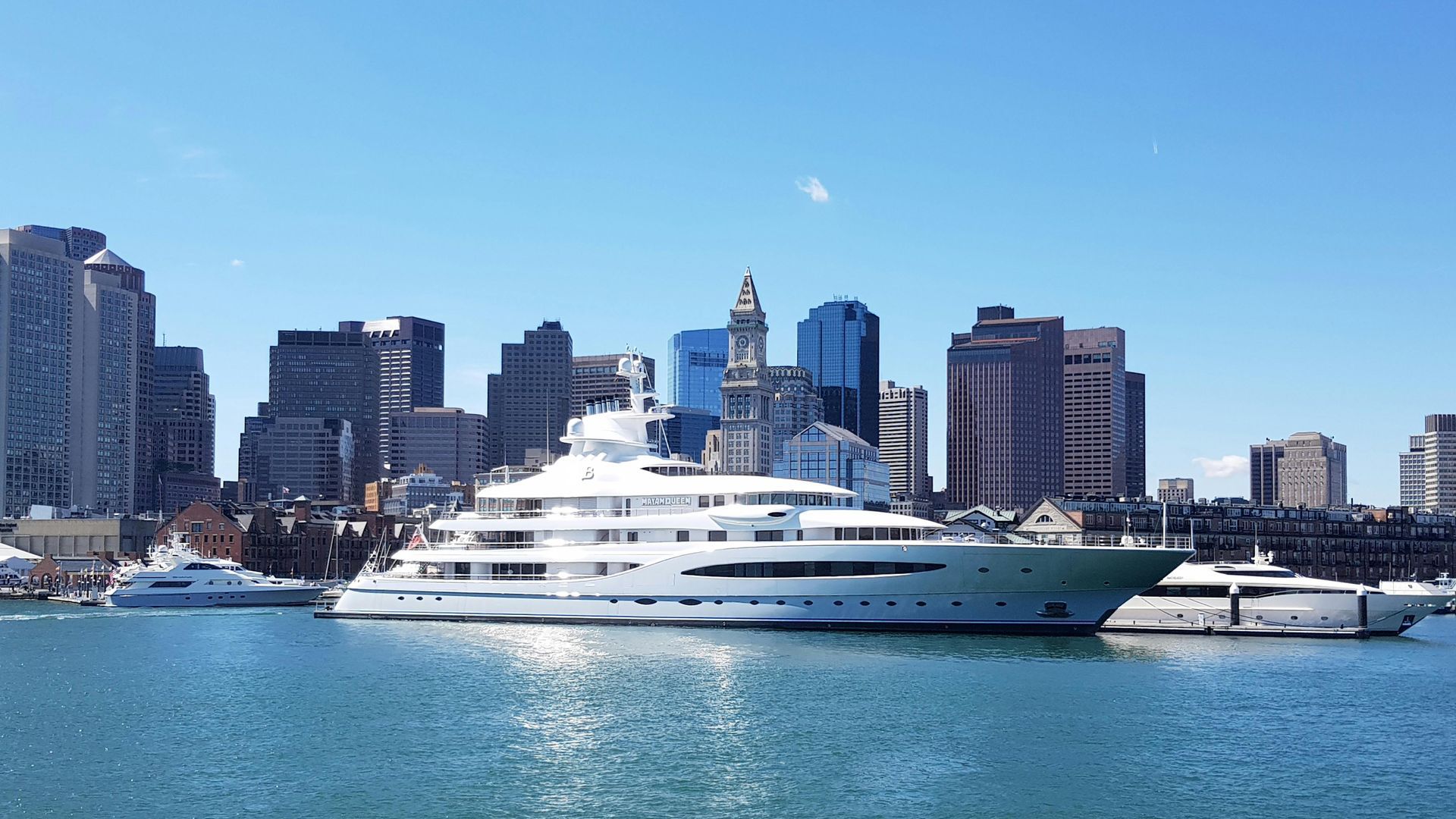 A large yacht is docked in front of a city skyline