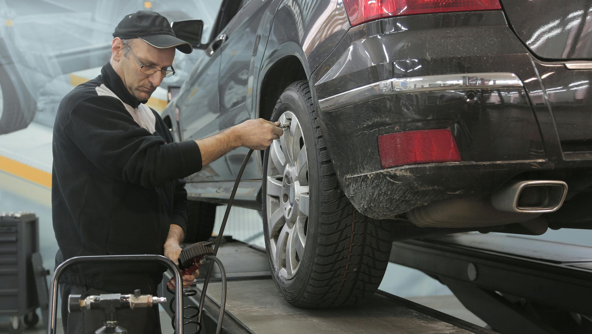 A man is changing a tire on a car in a garage.