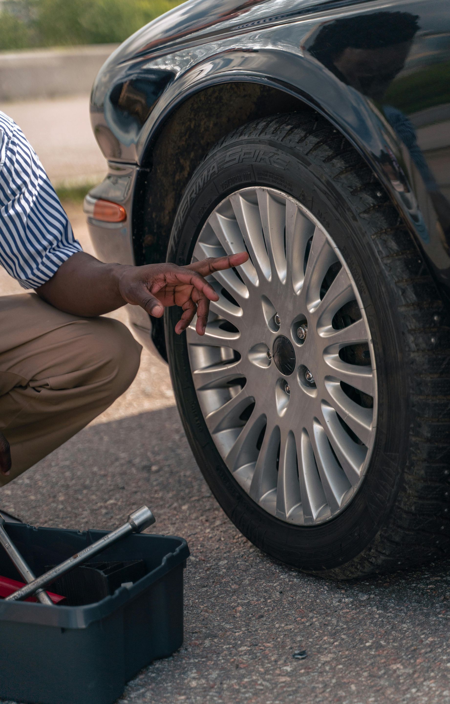 A man is kneeling down to change a tire on a car.