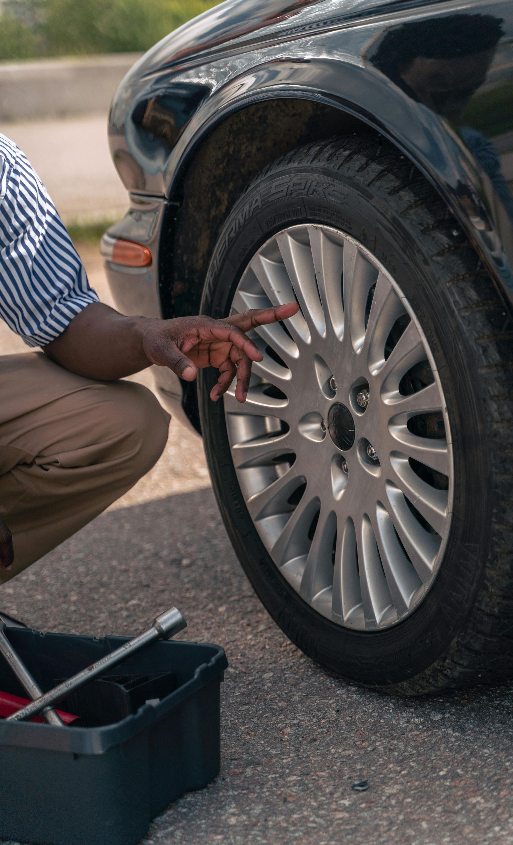 A man is kneeling down to change a tire on a car.