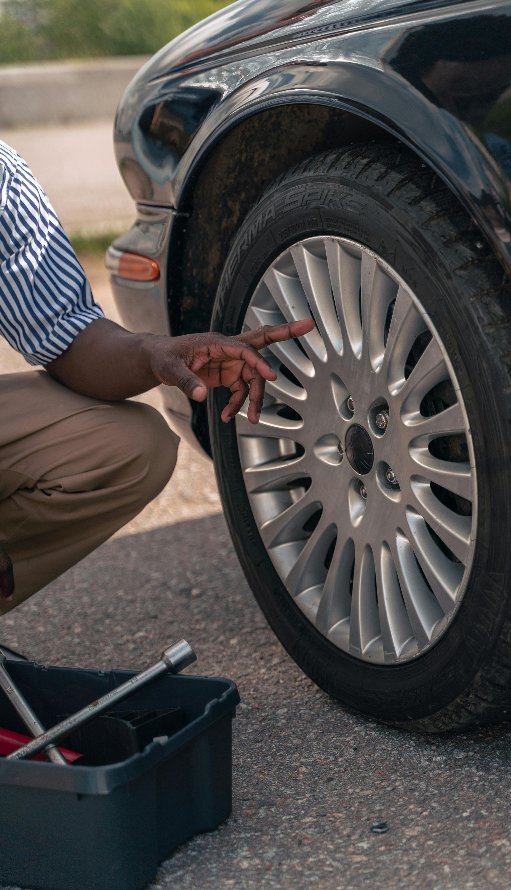 A man is kneeling down to change a tire on a car.