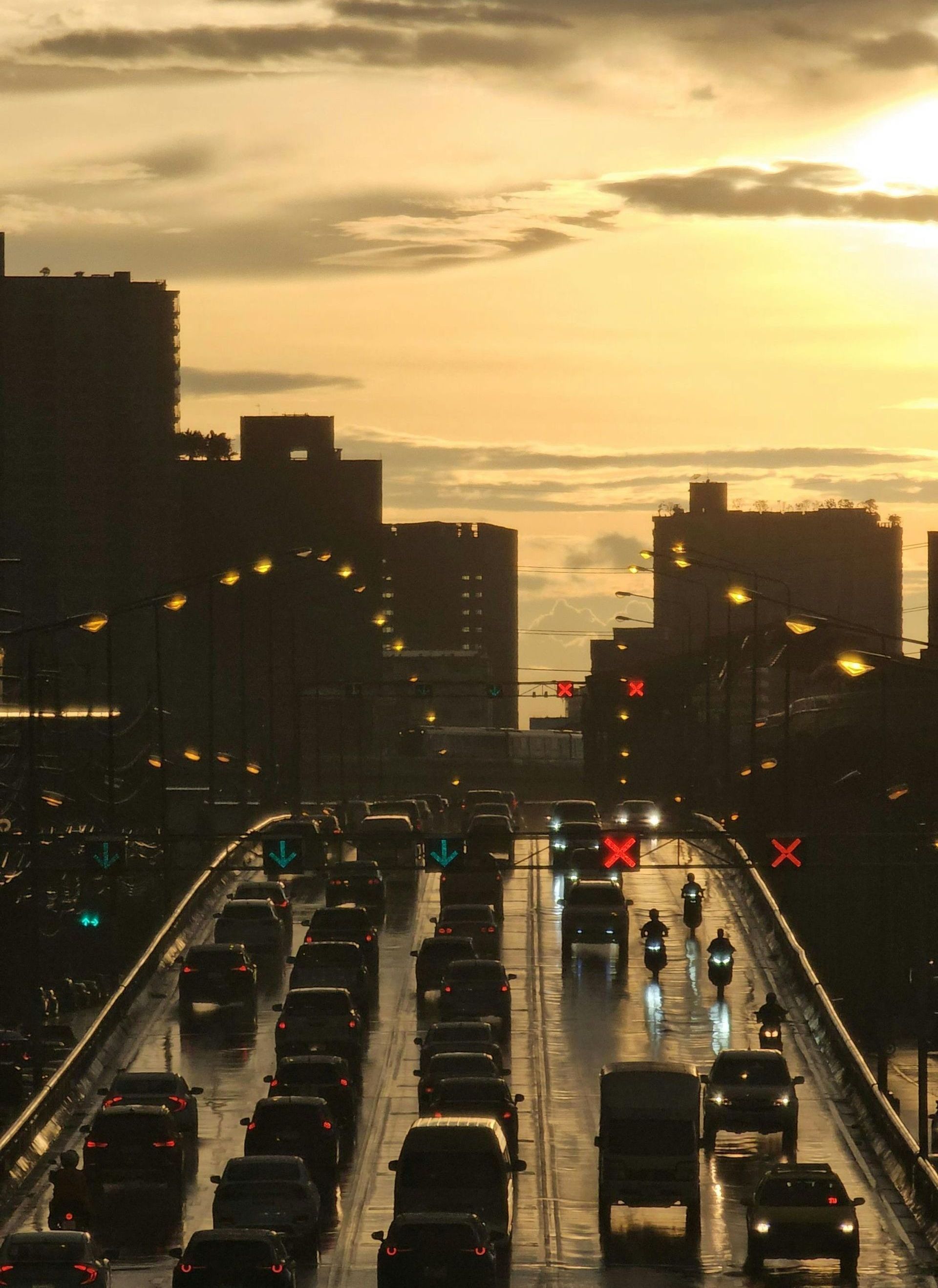 A lot of cars are driving in a city at sunset