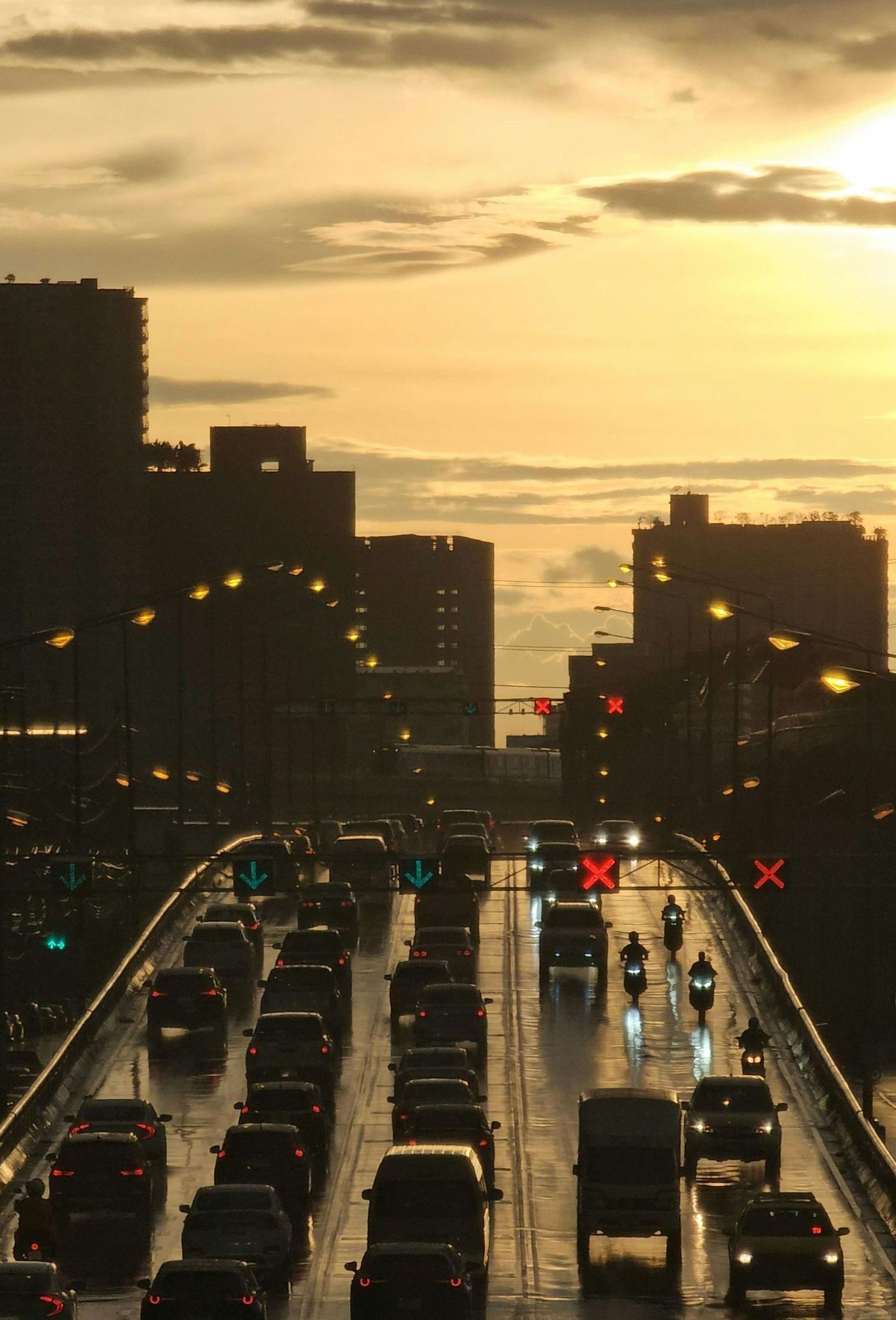A lot of cars are driving in a city at sunset