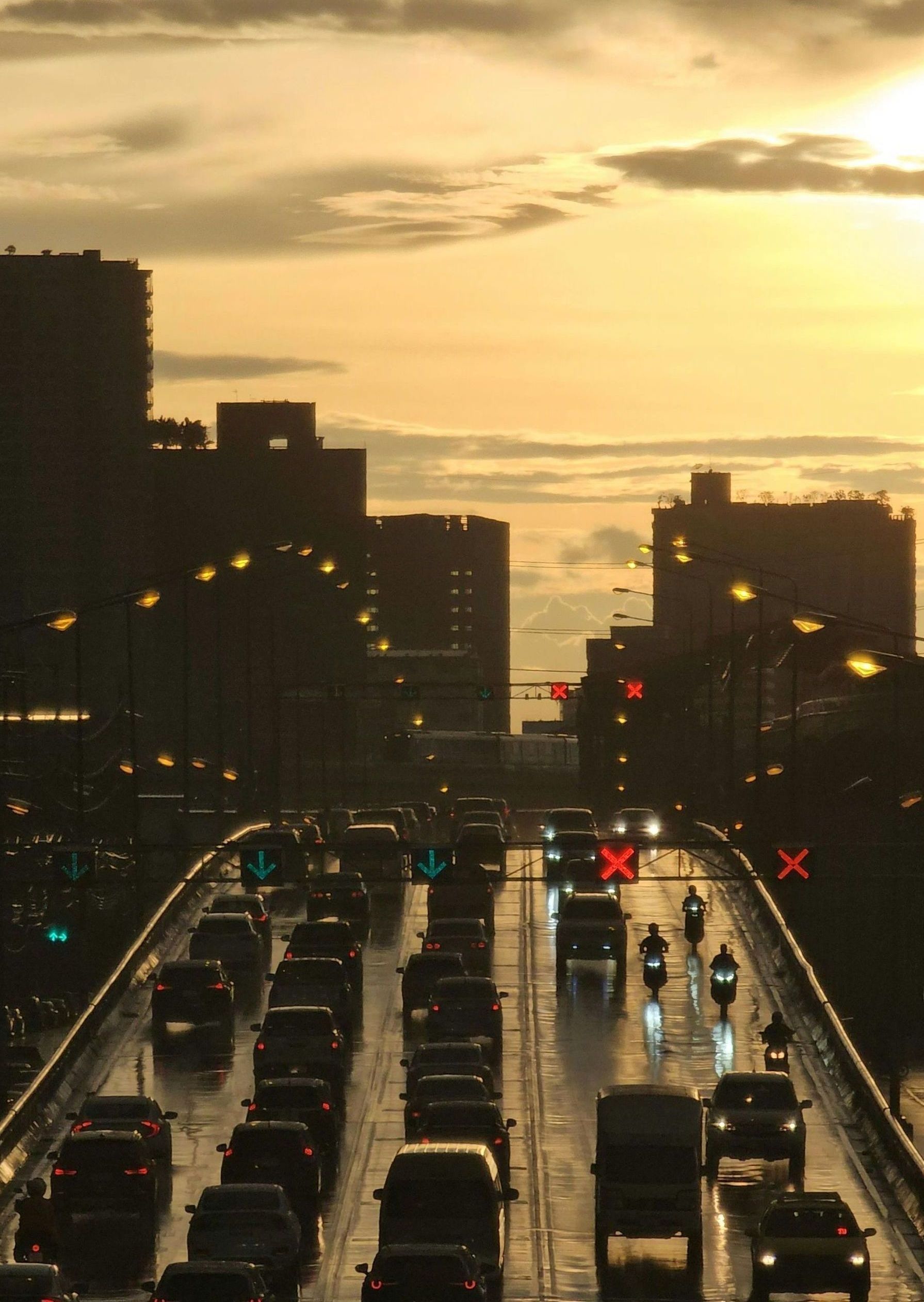 A lot of cars are driving in a city at sunset